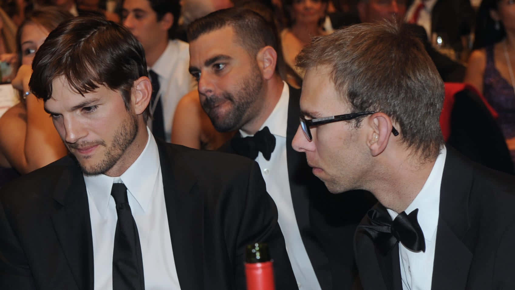 三位正式穿著禮服的男人坐在活動中，低頭。
