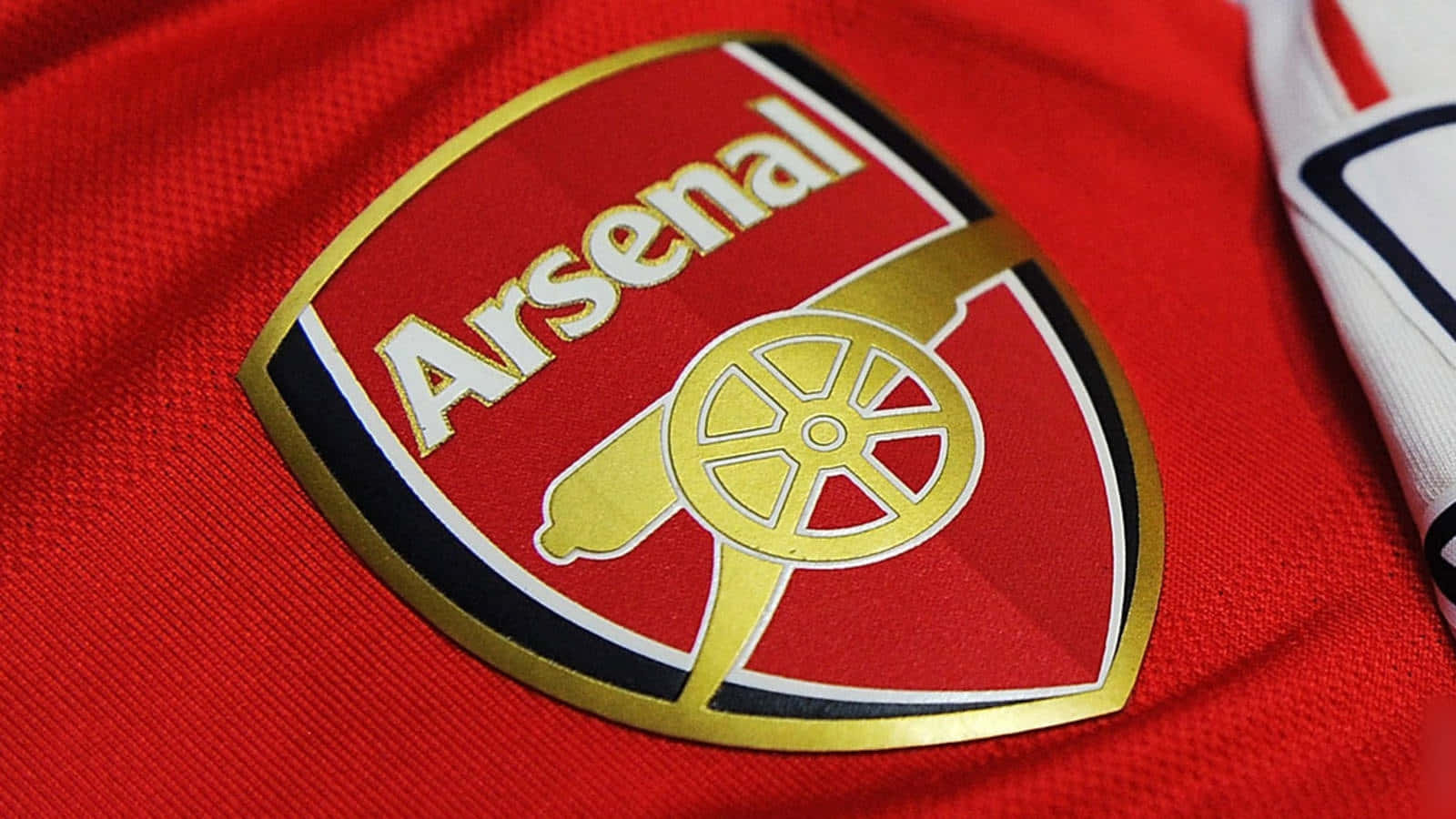 Arsenal 桌布 壁紙 — 阿仙奴足球會徽章以金線和白色線繡在質感豐富的紅色球衣上的特寫。