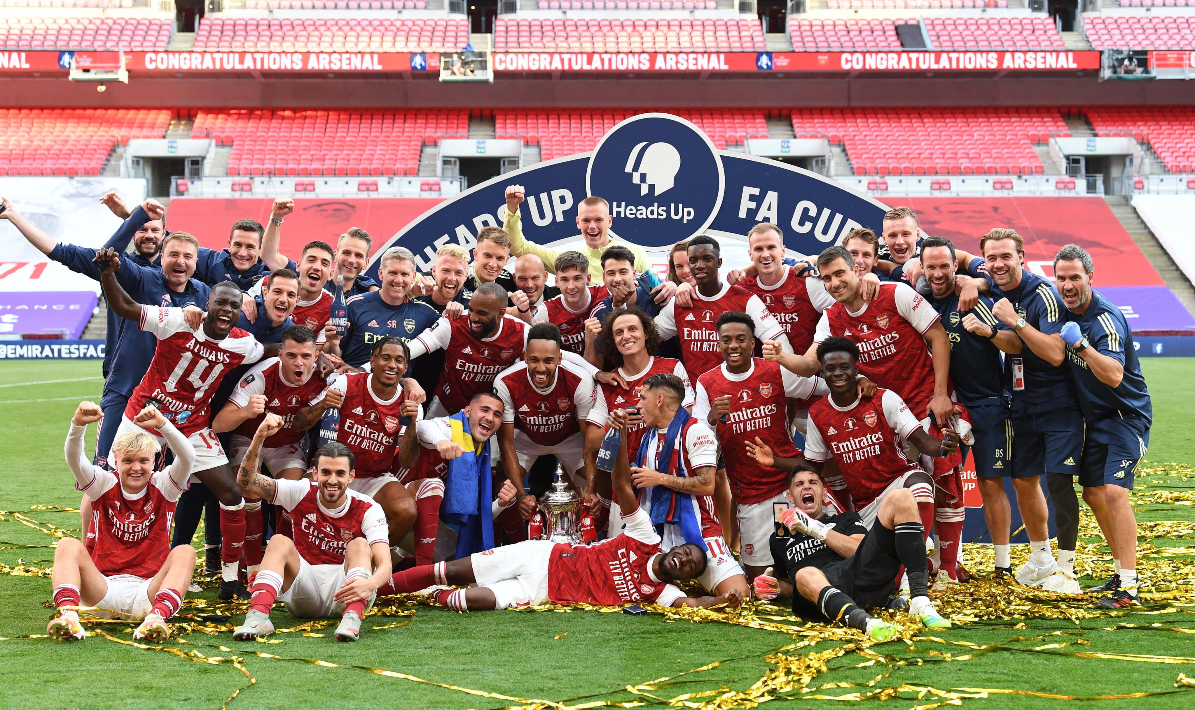 Arsenal 桌布 壁紙 — 阿仙奴足球隊在球場草地上慶祝勝利，手持獎盃並有五彩紙屑。