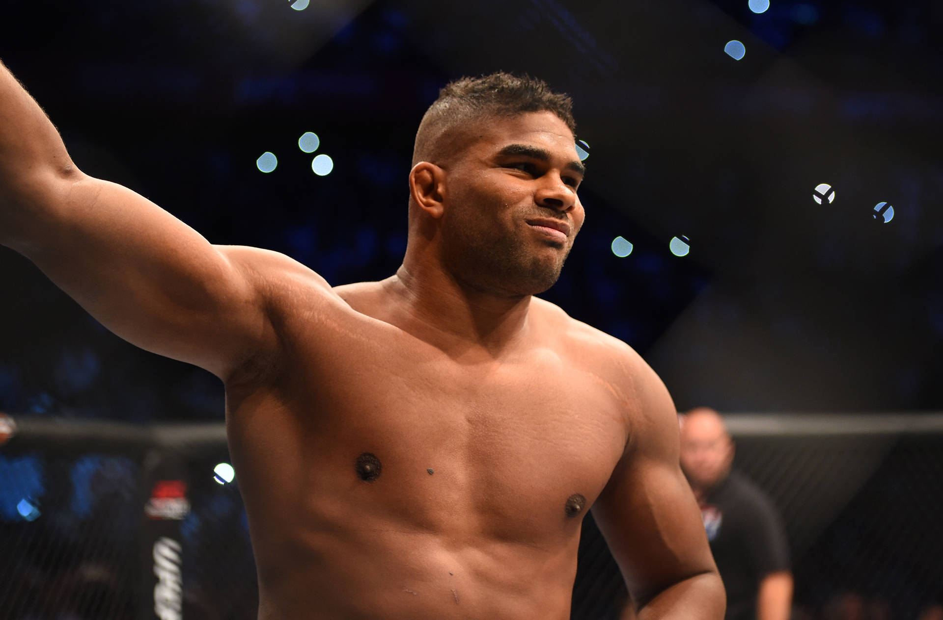 一位勝利的MMA戰士在競技場燈光下於八角籠中舉起手臂。