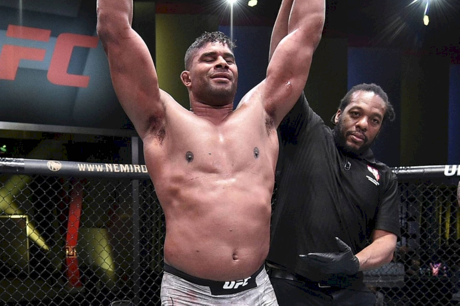 UFC拳手在八角籠內高舉雙臂慶祝勝利。