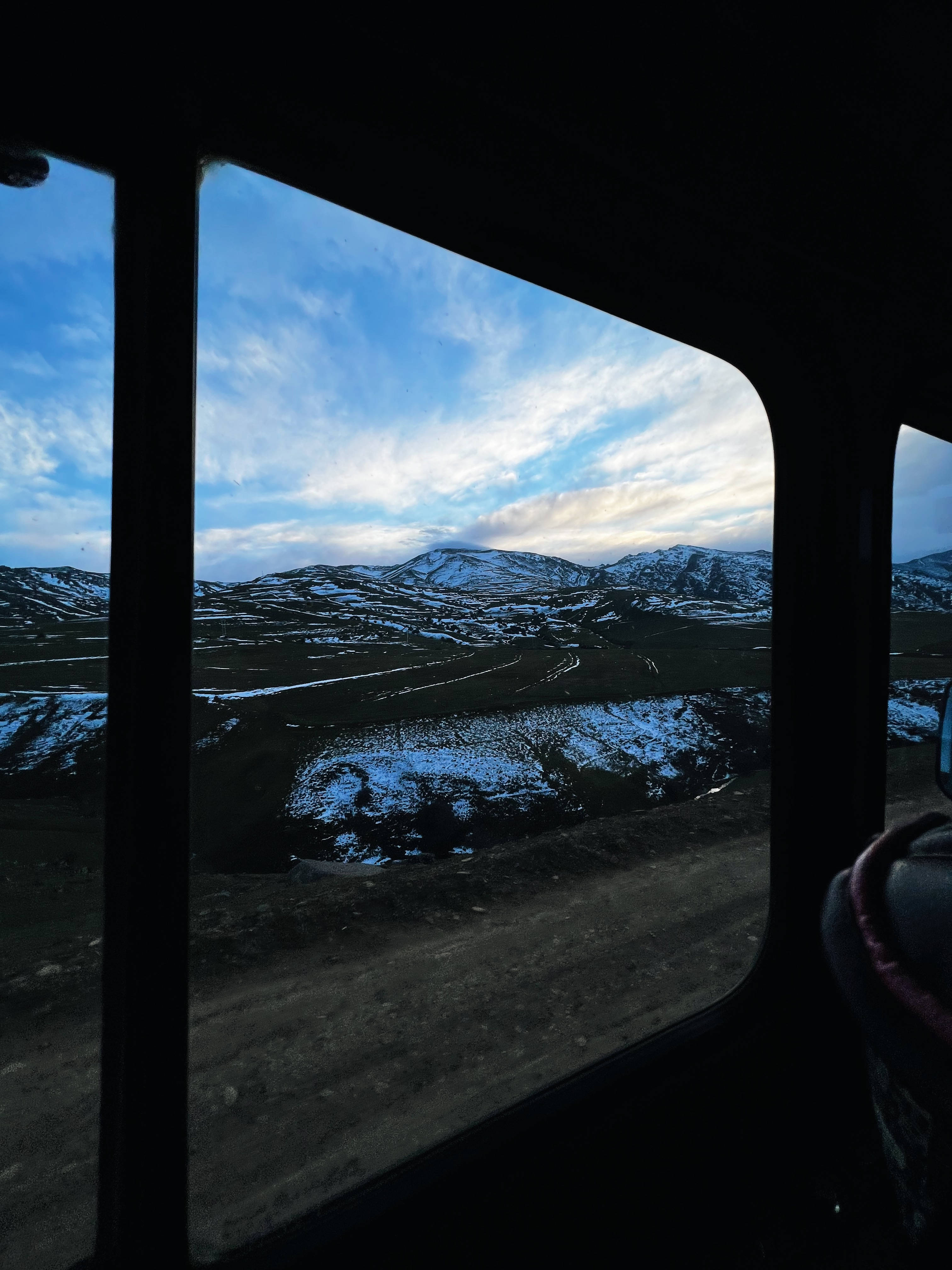阿塞拜疆窗邊風景 壁紙 — 黃昏時透過車窗看到的積雪山脈和蜿蜒道路。