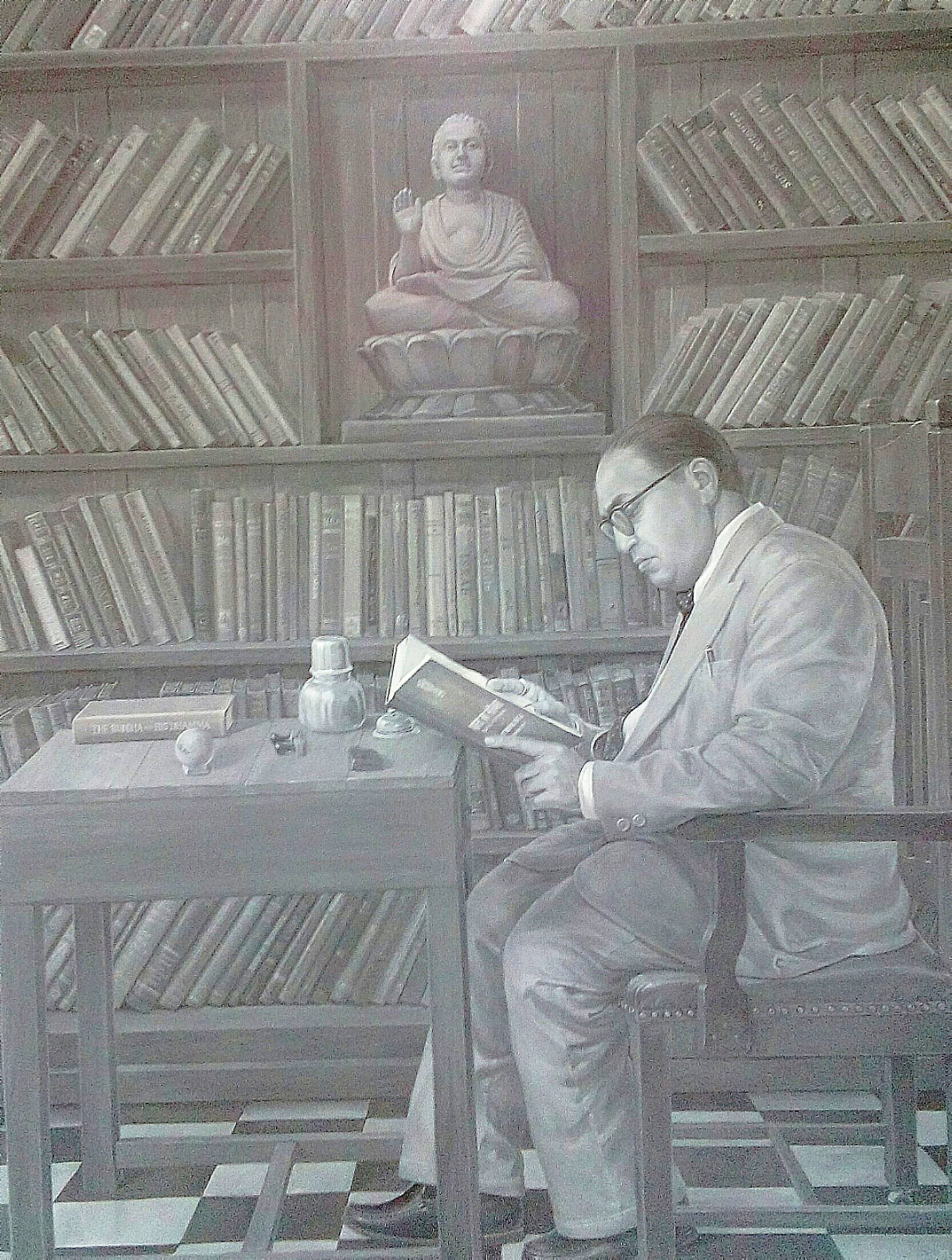 戴眼鏡男子在單色圖書館中看書，旁邊有佛像。