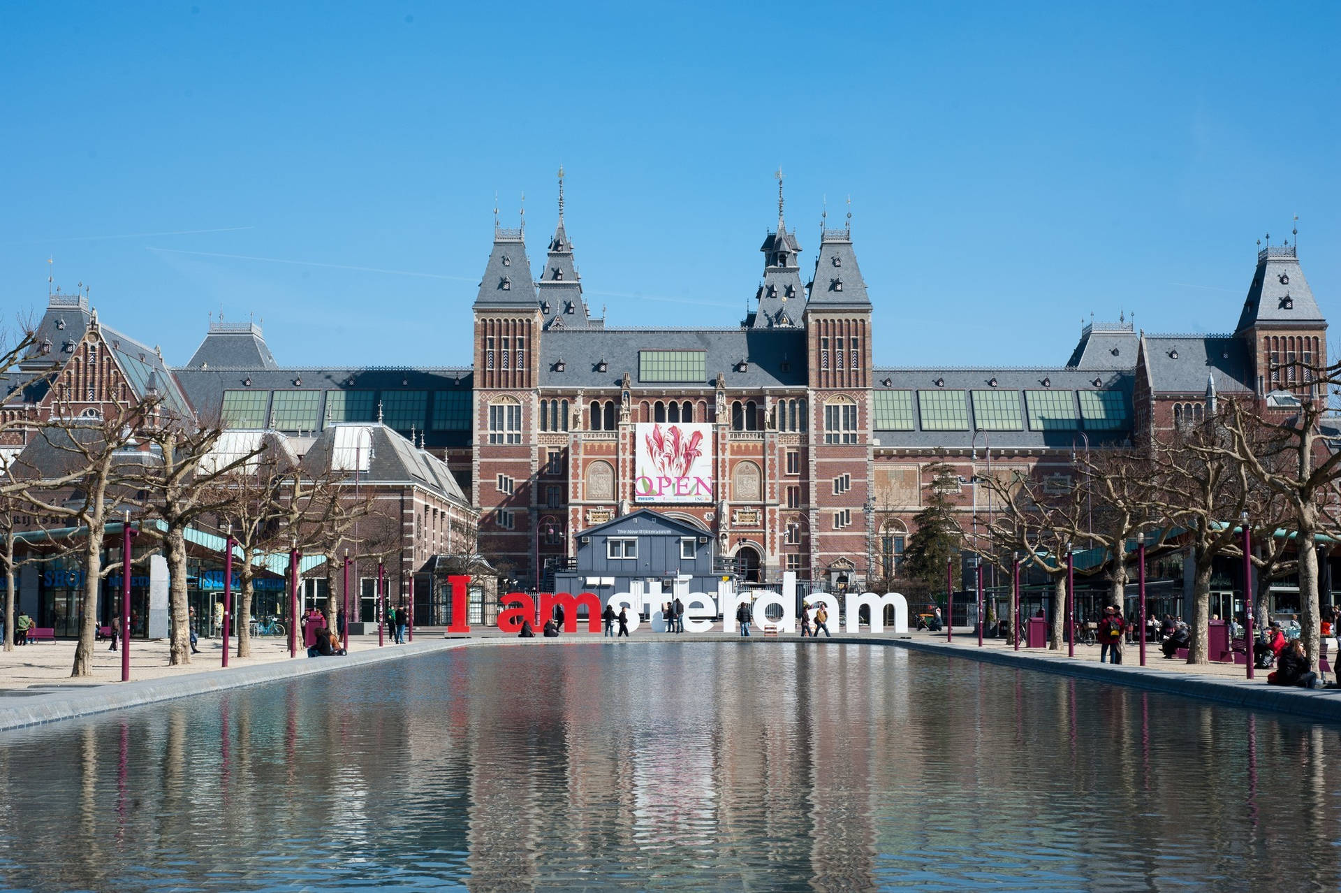 阿姆斯特丹國立博物館與「I am Amsterdam」標誌在陽光下倒映在水中。