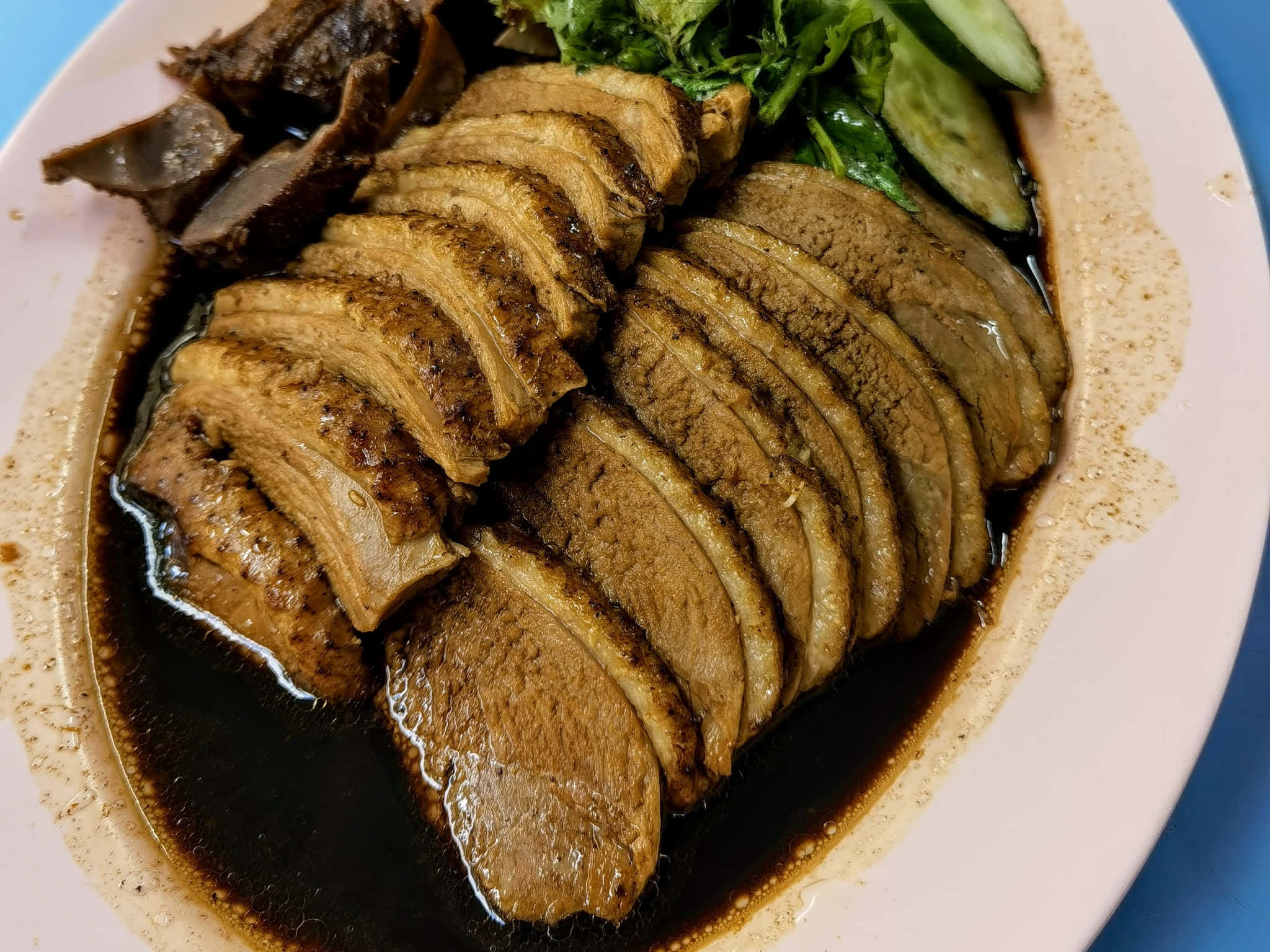 阿小潮州鴨肉飯攤位招牌菜 壁紙 — 白碟上嘅切片燜鴨，用深色醬汁上色，配新鮮蔬菜同青瓜。