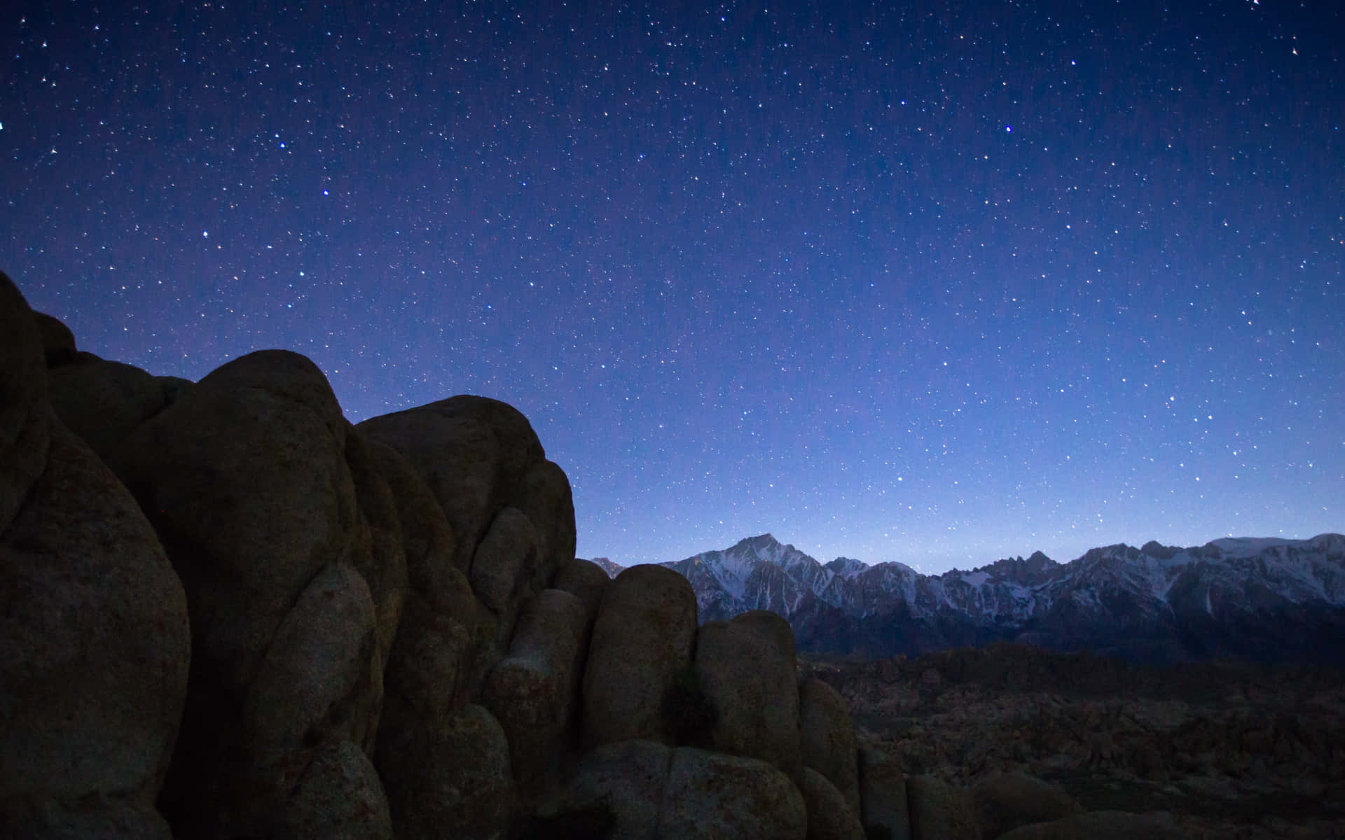 積雪覆蓋的山脈和沙漠巨石之上的繁星之夜