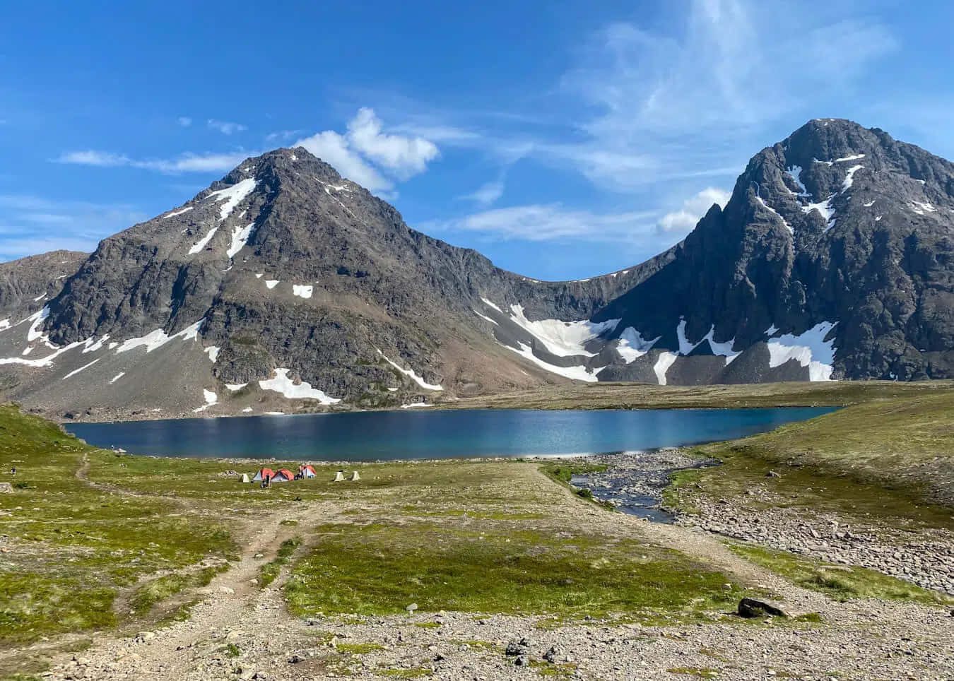 阿拉斯加安克雷奇兔子湖露營風景 壁紙 — 寧靜的高山湖泊，坐落於積雪的山峰之間，草地上有一個小露營地，上方是清澈的藍天。