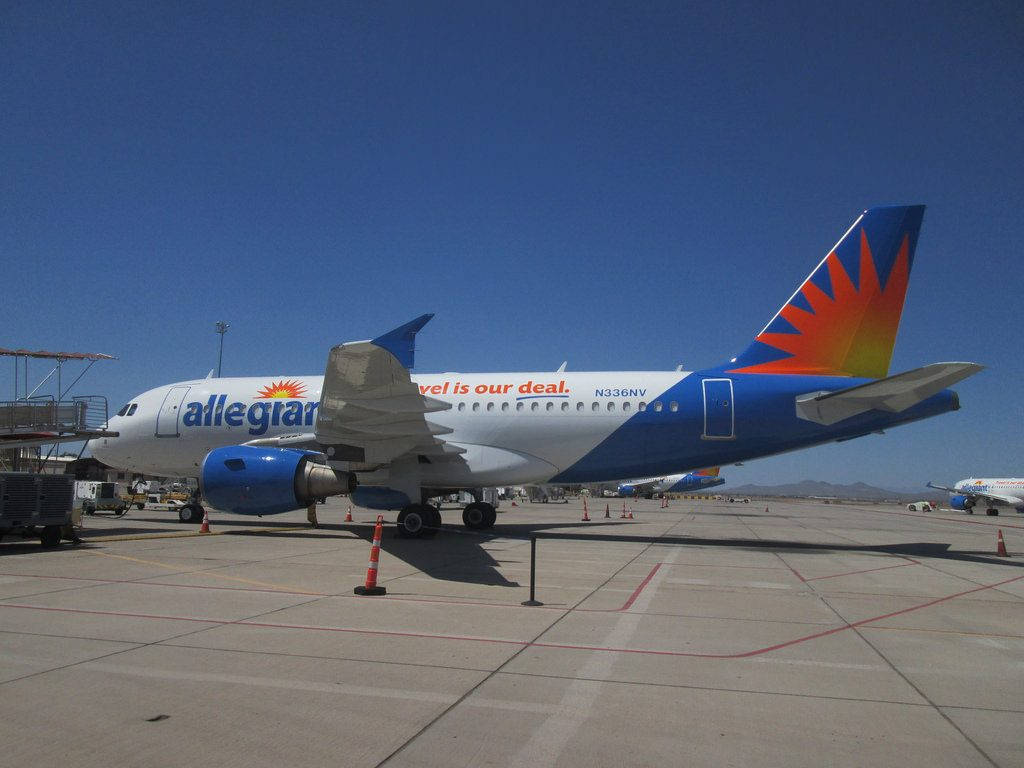 Allegiant Airlines 飛機停泊在機場停機坪上，天空清澈湛藍。