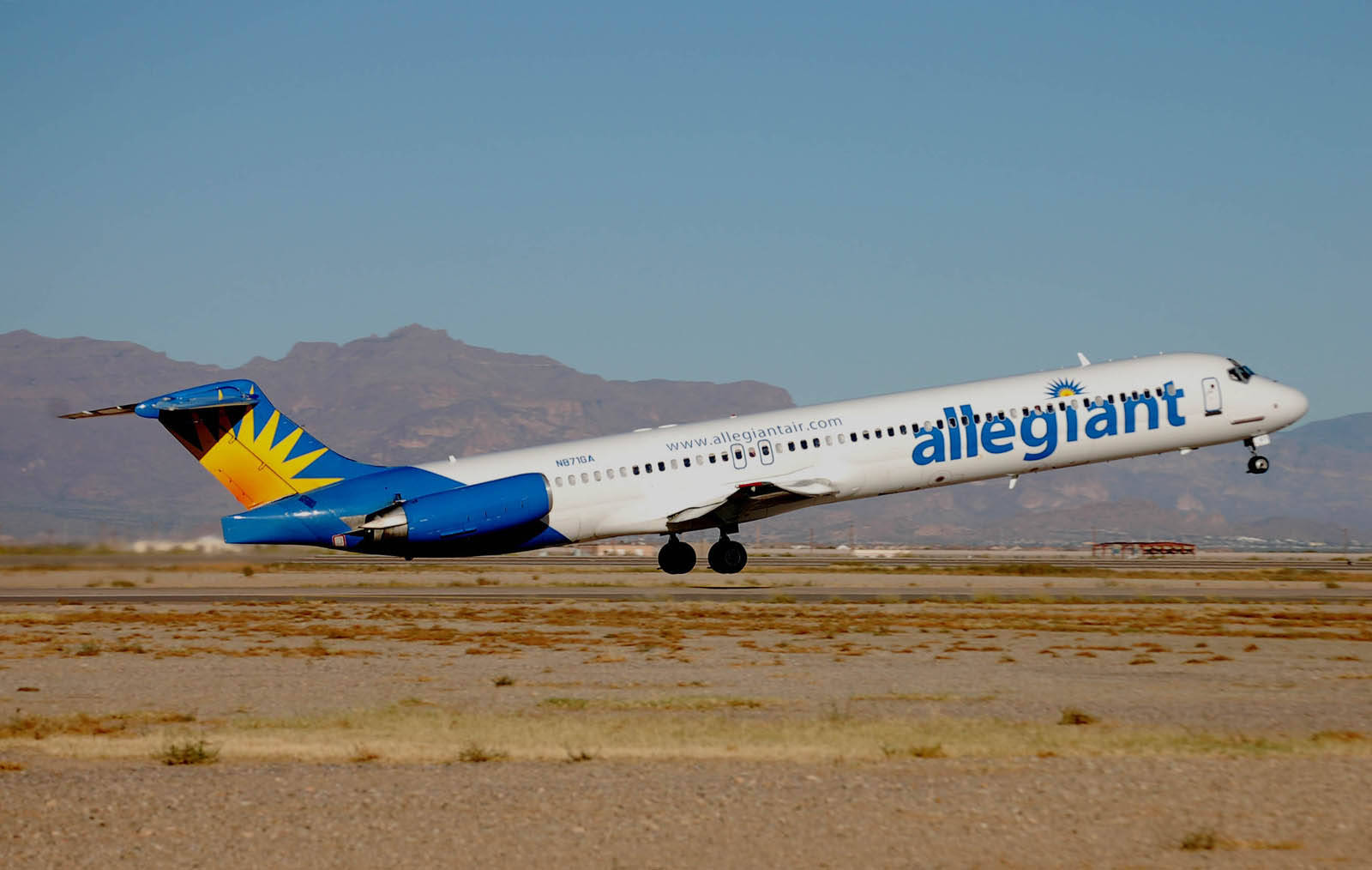 Allegiant Air 飛機從沙漠跑道起飛，背景有山脈。