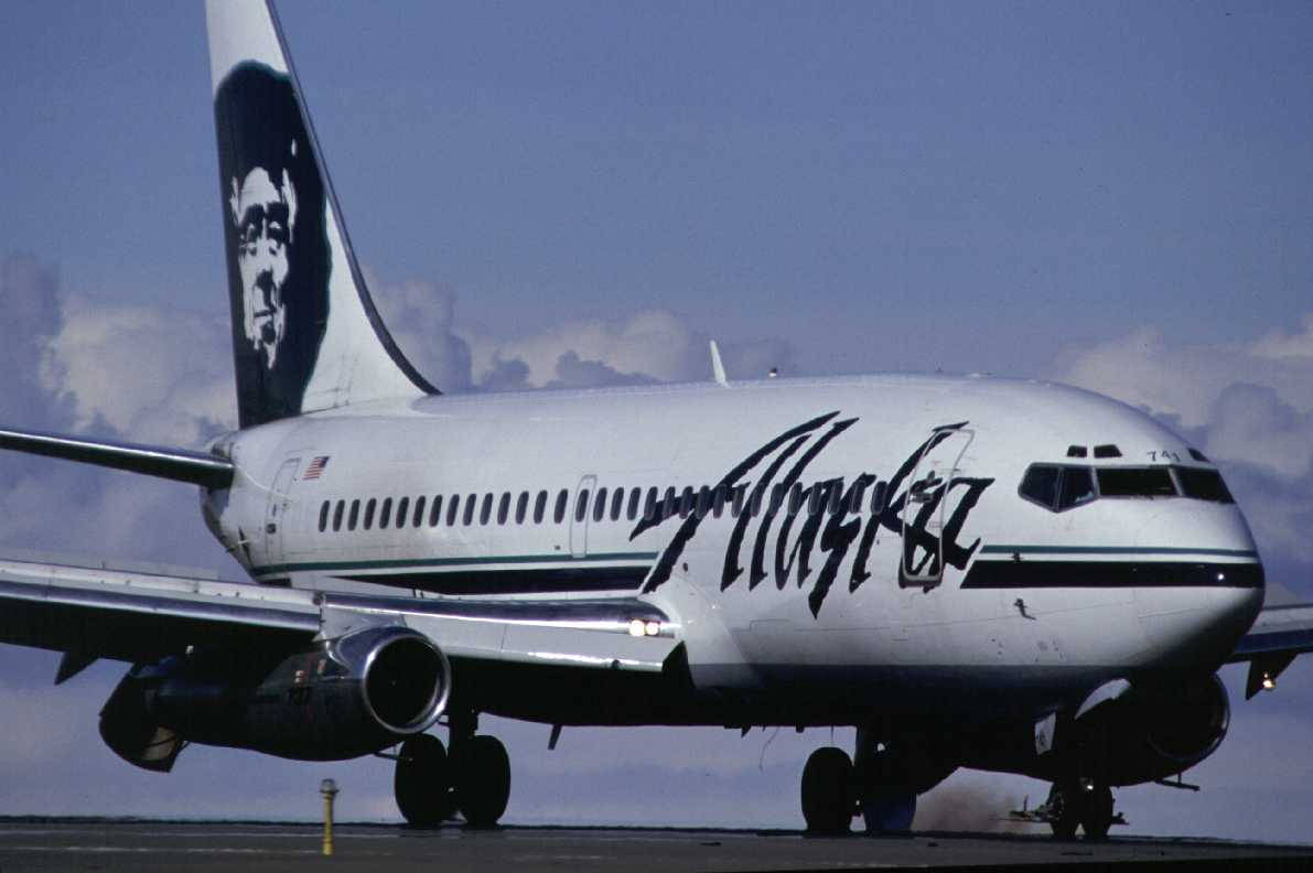 阿拉斯加航空噴射機停在機場停機坪，機尾有面部標誌。