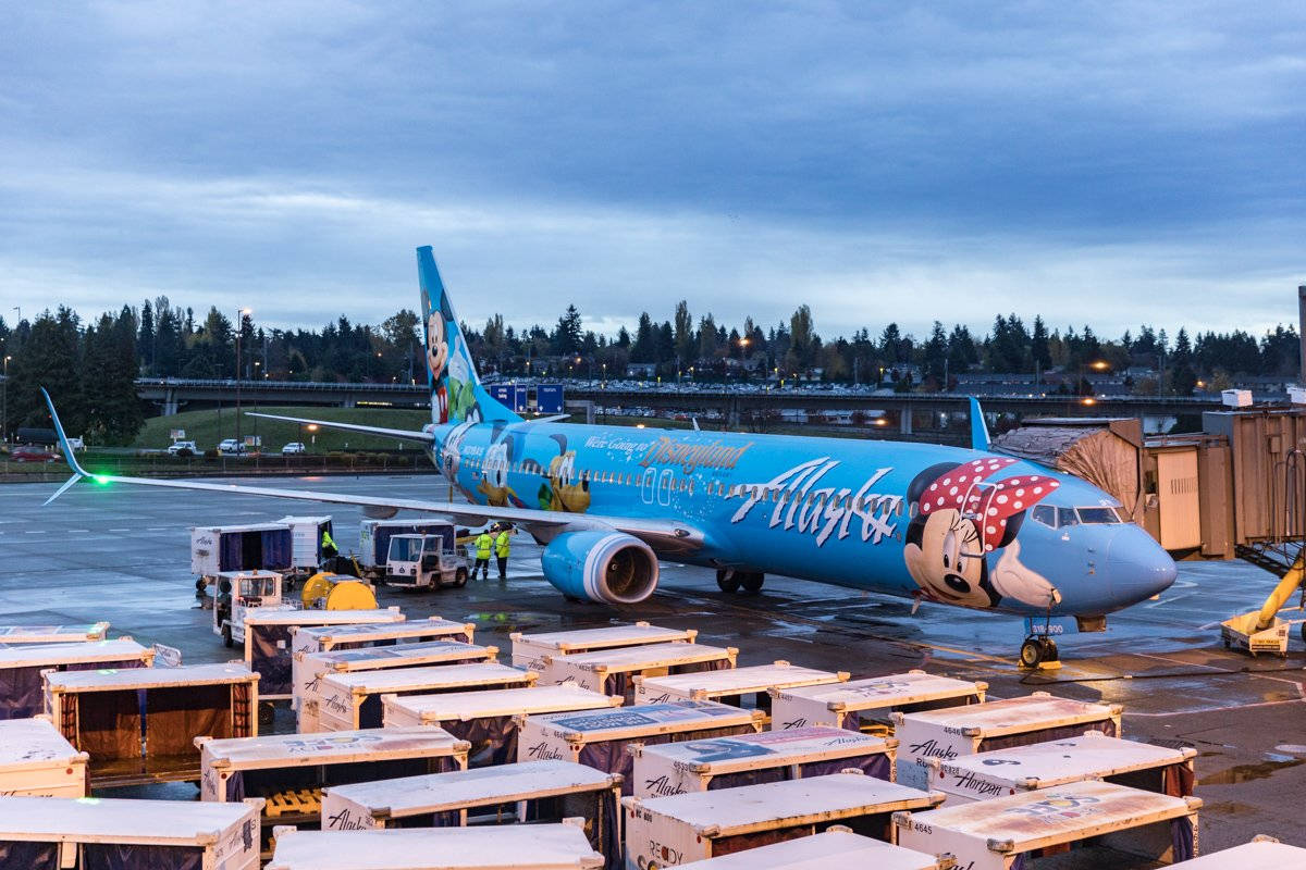 阿拉斯加航空飛機帶有迪士尼角色，在黃昏時停泊在機場閘口。