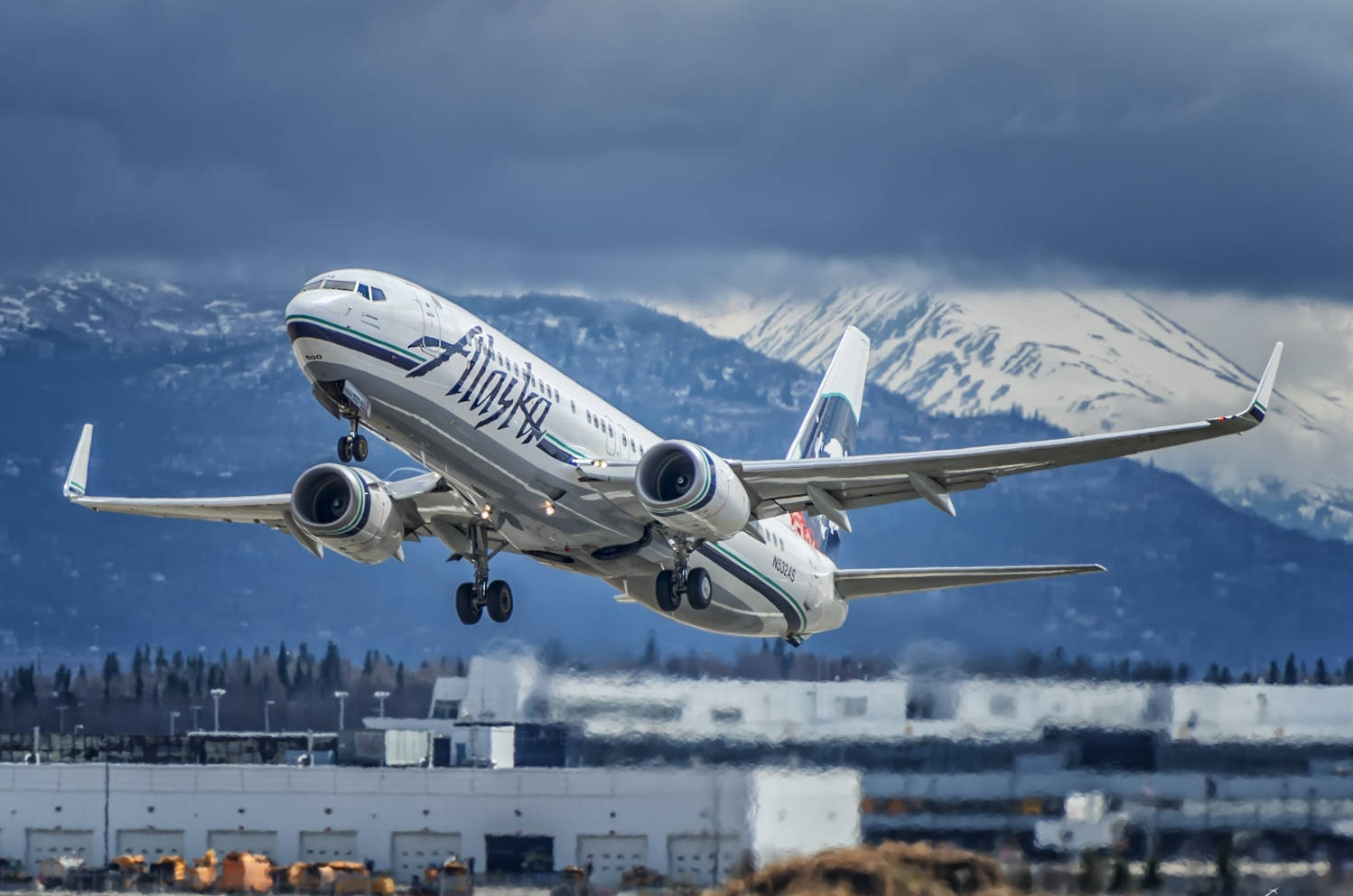 阿拉斯加航空飛機起飛，背景是積雪的山脈。