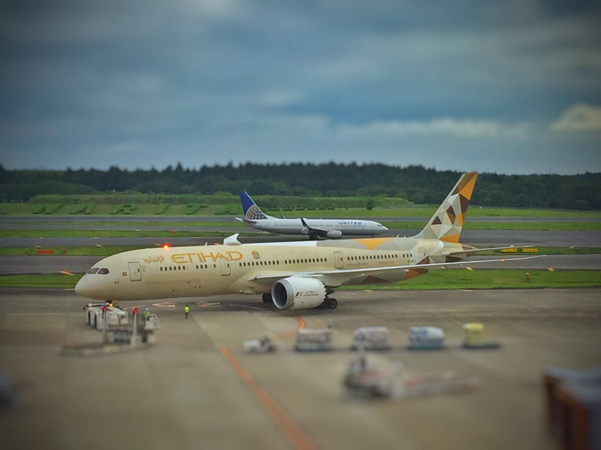 阿提哈德航空飛機在機場停機坪上，背景有另一架飛機，天空多雲
