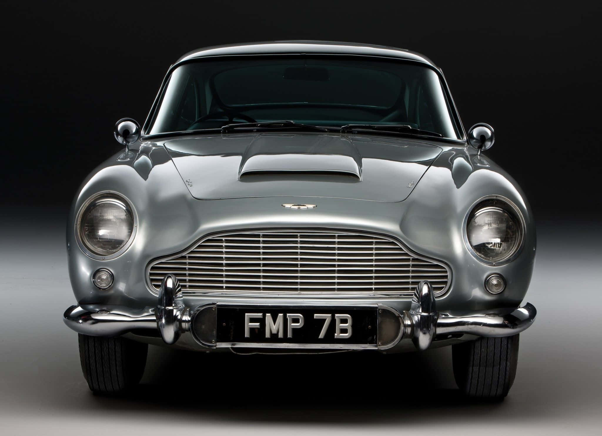 阿斯頓·馬丁 DB5 — 經典永恆 壁紙 — 一輛流線型的銀色Aston Martin DB5在攝影棚燈光下閃耀，帶有鍍鉻飾邊和標誌性格柵。