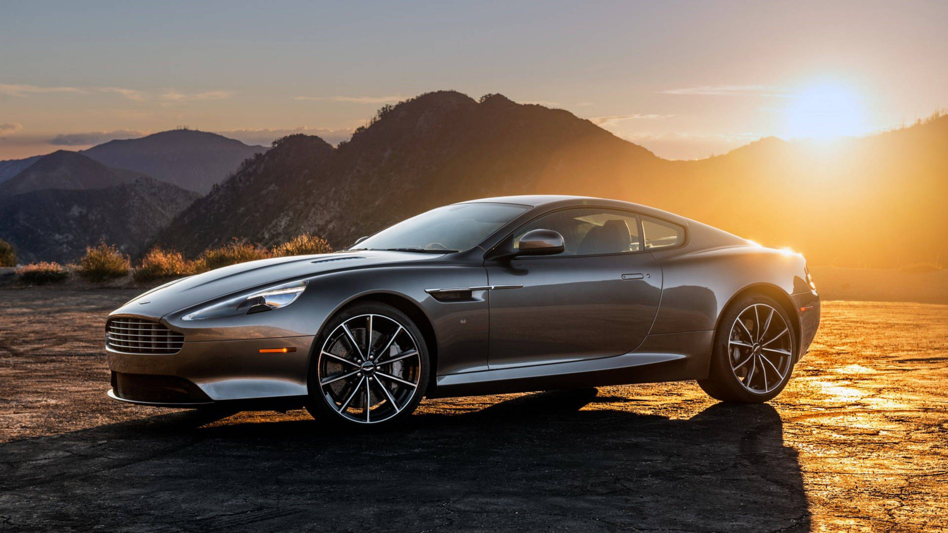 銀色Aston Martin跑車停在日落時分的山路上。