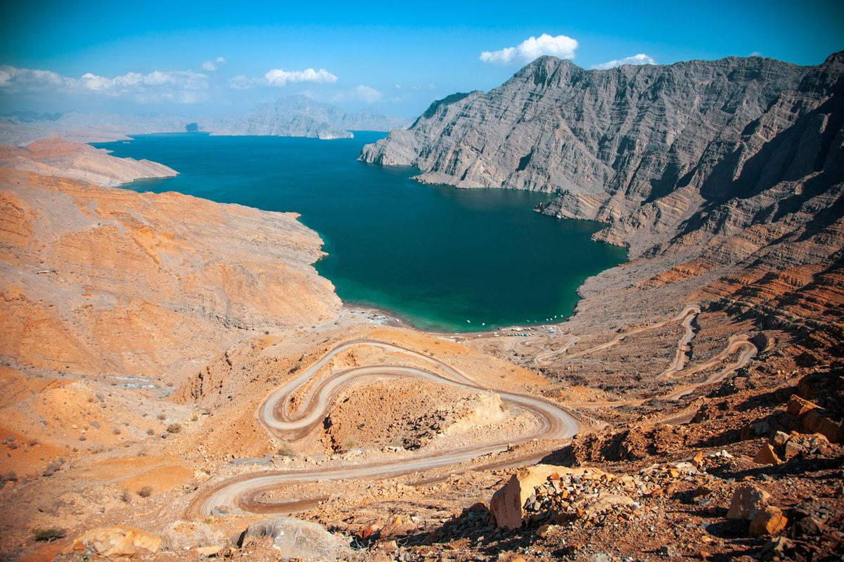 蜿蜒的道路穿過沙漠山脈，在日落時分通往碧綠的海洋。