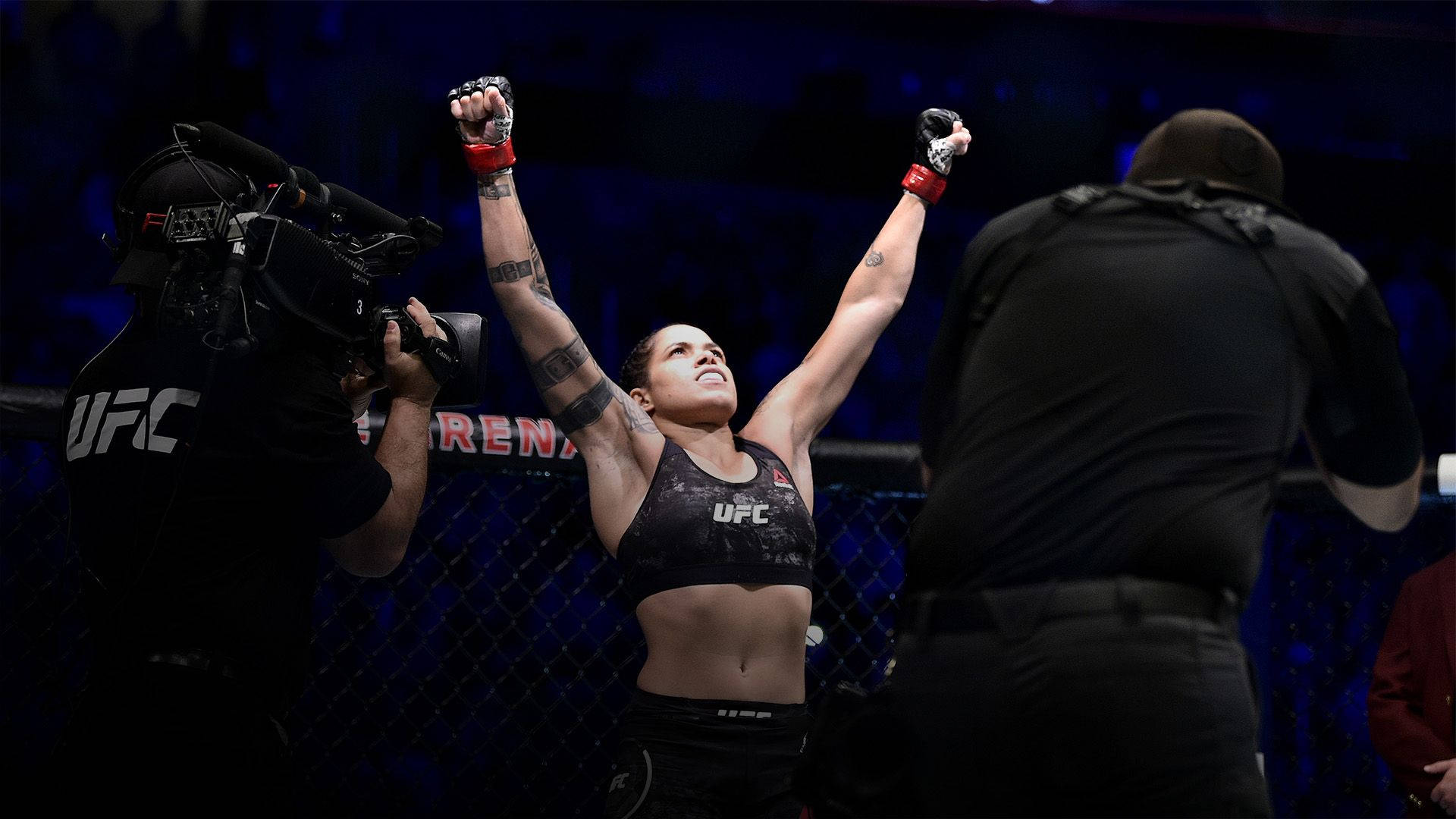 女性MMA拳手在UFC八角籠內高舉雙臂慶祝勝利。