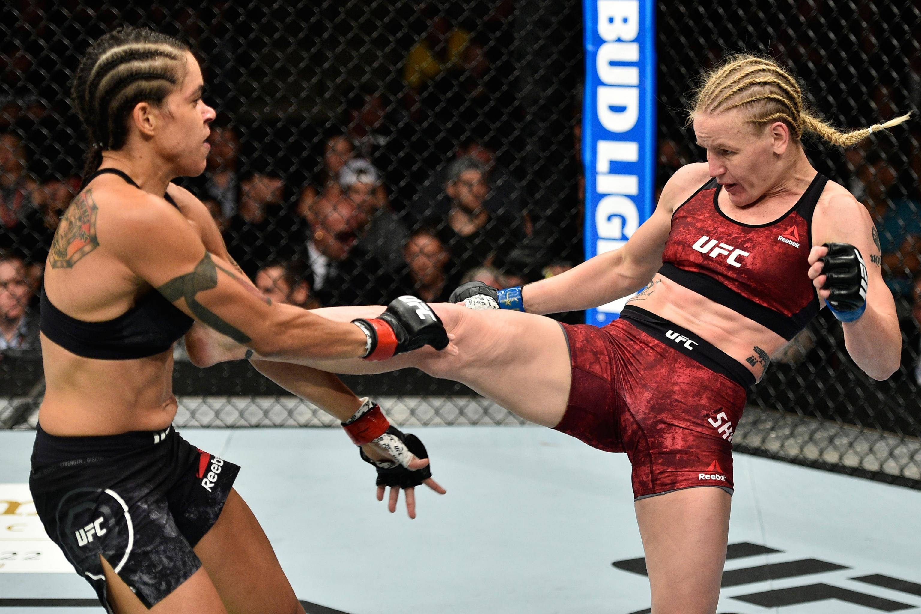 阿曼達·努內斯對戰瓦倫蒂娜·舍夫琴科 壁紙 — 兩名女性MMA拳手在激烈的籠鬥中交鋒，其中一人使出高踢。