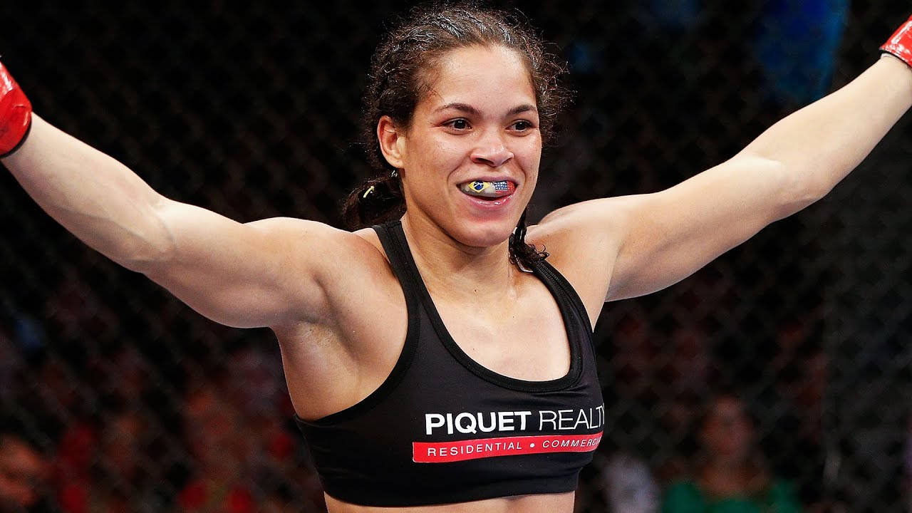 女性MMA拳手在八角籠中舉起雙臂慶祝勝利。