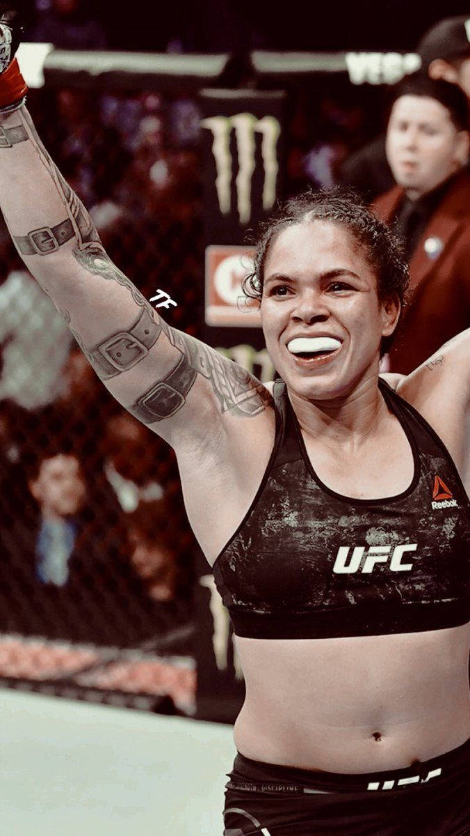 女MMA拳手在UFC八角籠內舉臂慶祝勝利。
