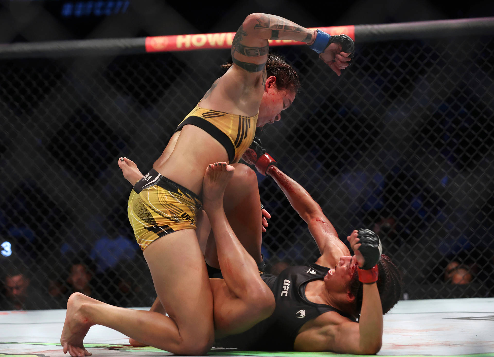 阿曼達·努內斯擊打茱莉安娜·佩納 壁紙 — 兩名女性MMA拳手在籠中激烈纏鬥，其中一人施展降服技。