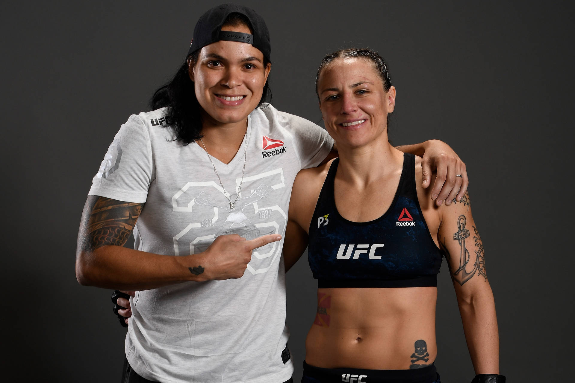 兩位女性UFC拳手穿著攝影棚服裝一起擺姿勢，紋身清晰可見。