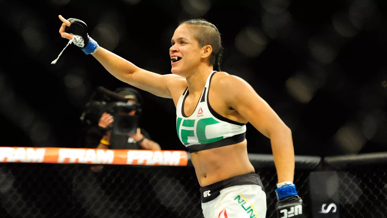 女性MMA拳手在八角籠中高舉拳頭慶祝勝利。