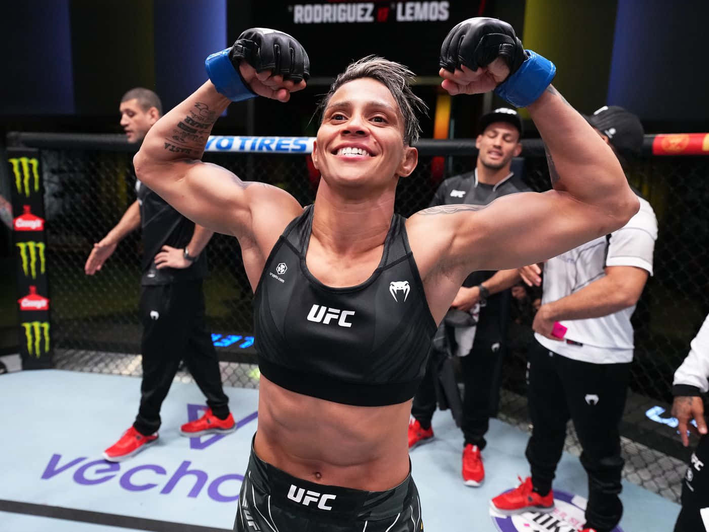 女性MMA拳手在UFC八角籠中高舉雙臂慶祝勝利。
