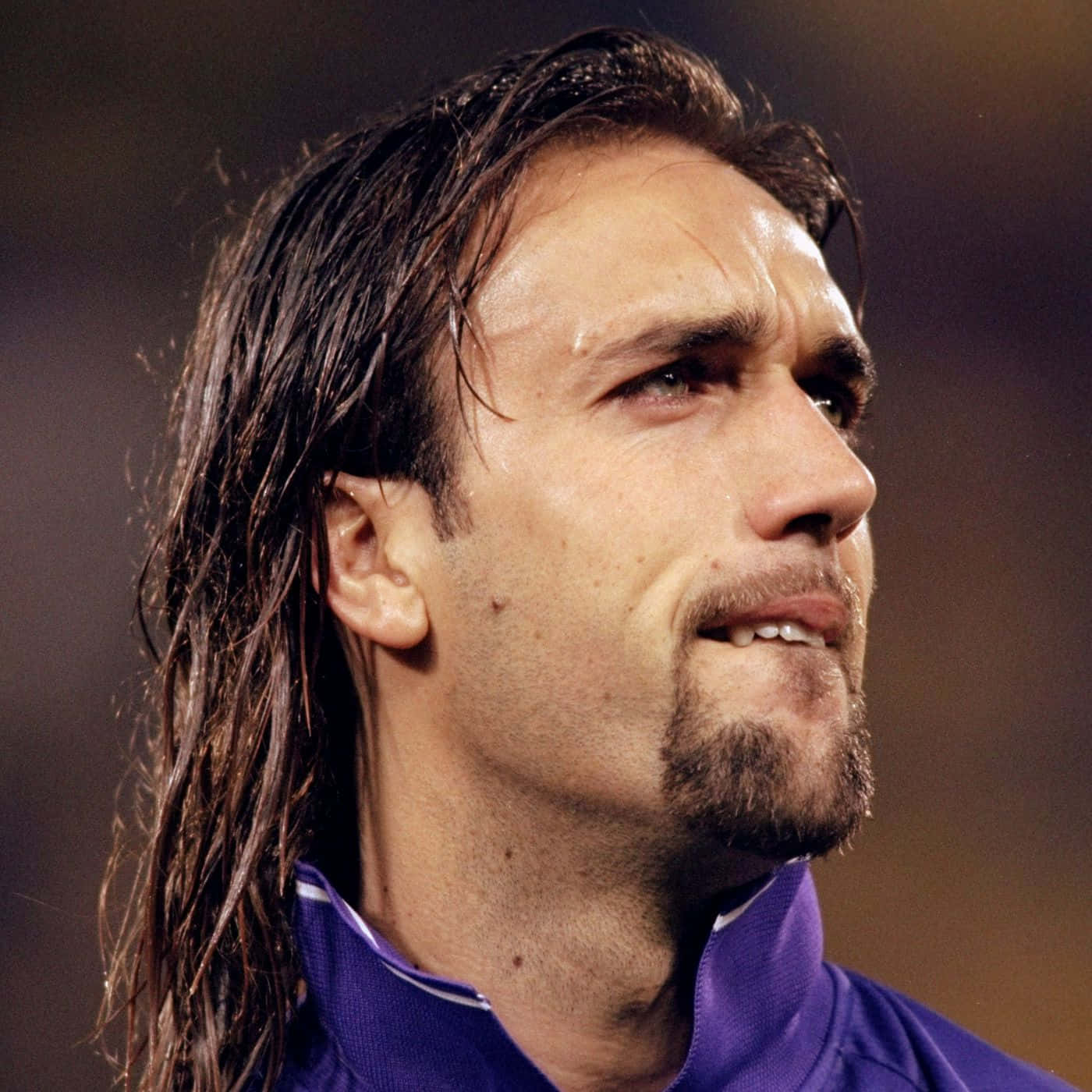 阿根廷足球員 Gabriel Batistuta 近照 壁紙 — 近距離拍攝一名汗流浹背的足球員，長黑髮、鬍鬚，在球場燈光下專注地向前望。