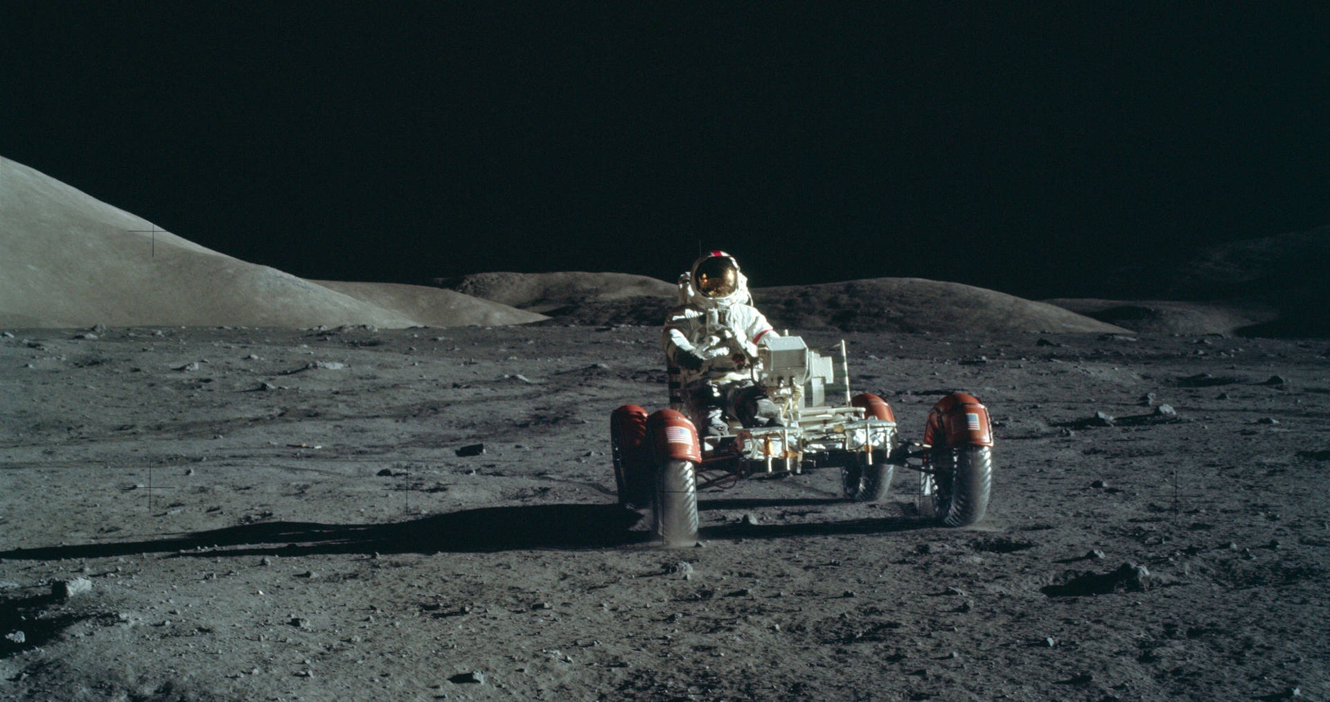 穿著月球裝備的太空人在灰色月球表面駕駛月球車。