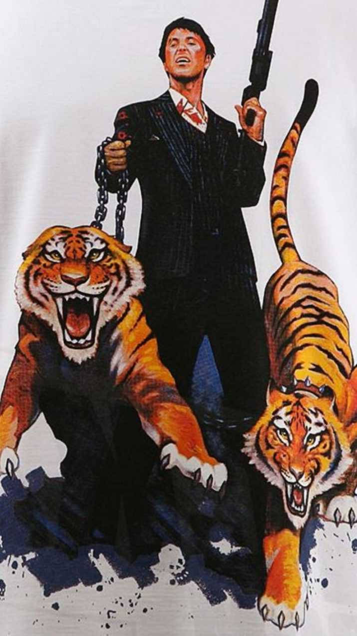 身穿西裝的男子手持槍支和鎖鏈，被兩隻咆哮的老虎包圍。
