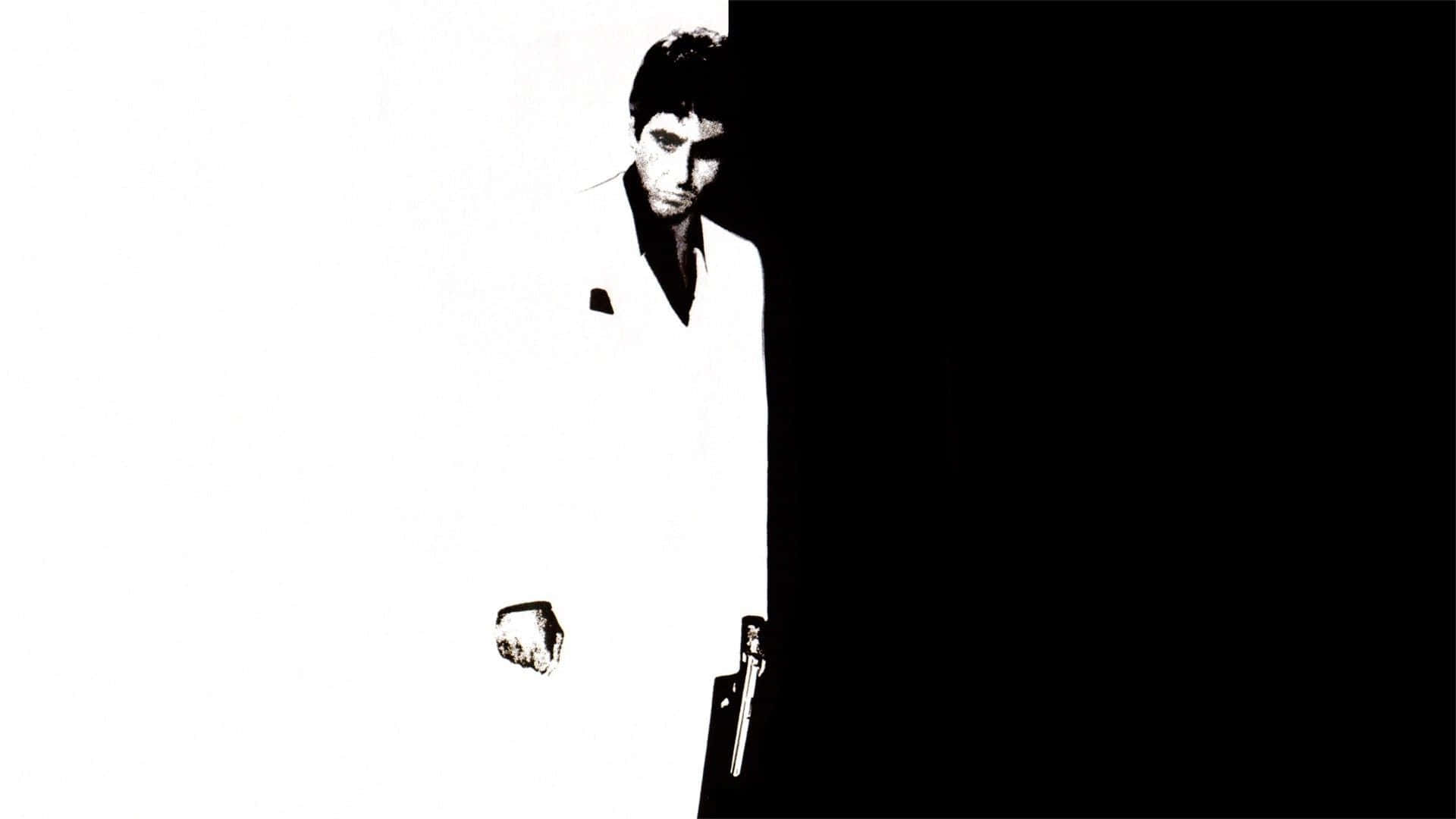 阿爾·帕西諾在經典電影《疤面煞星》中飾演 Tony Montana 壁紙 — 一名身穿白色西裝的男子站在強烈的黑白對比中，手持槍支，表情嚴肅。