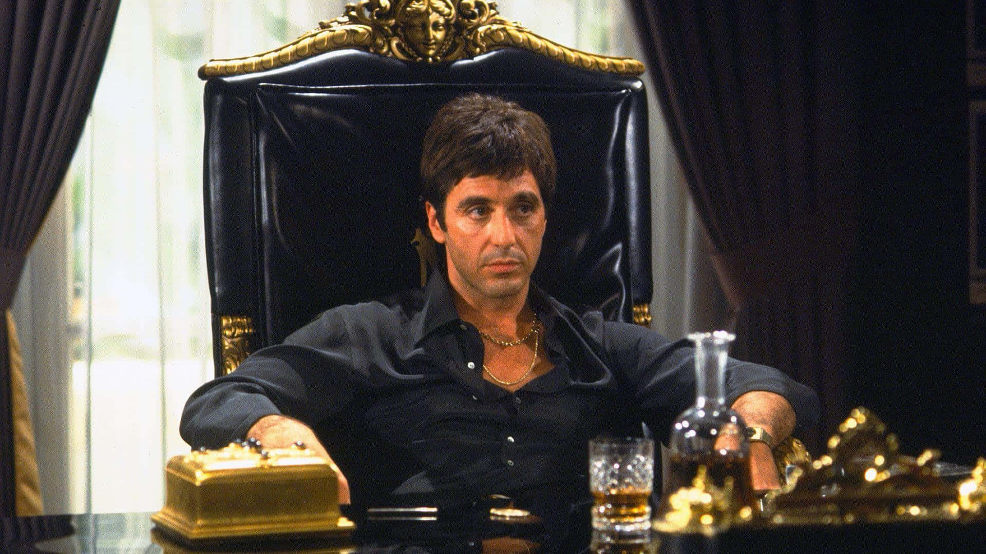 阿爾·帕西諾飾演《疤面煞星》中的 Tony Montana 壁紙 — 一名男子威嚴地坐在一張帶有金色裝飾的黑色皮革王座椅上，周圍環繞著華麗的金色物品和深色窗簾。