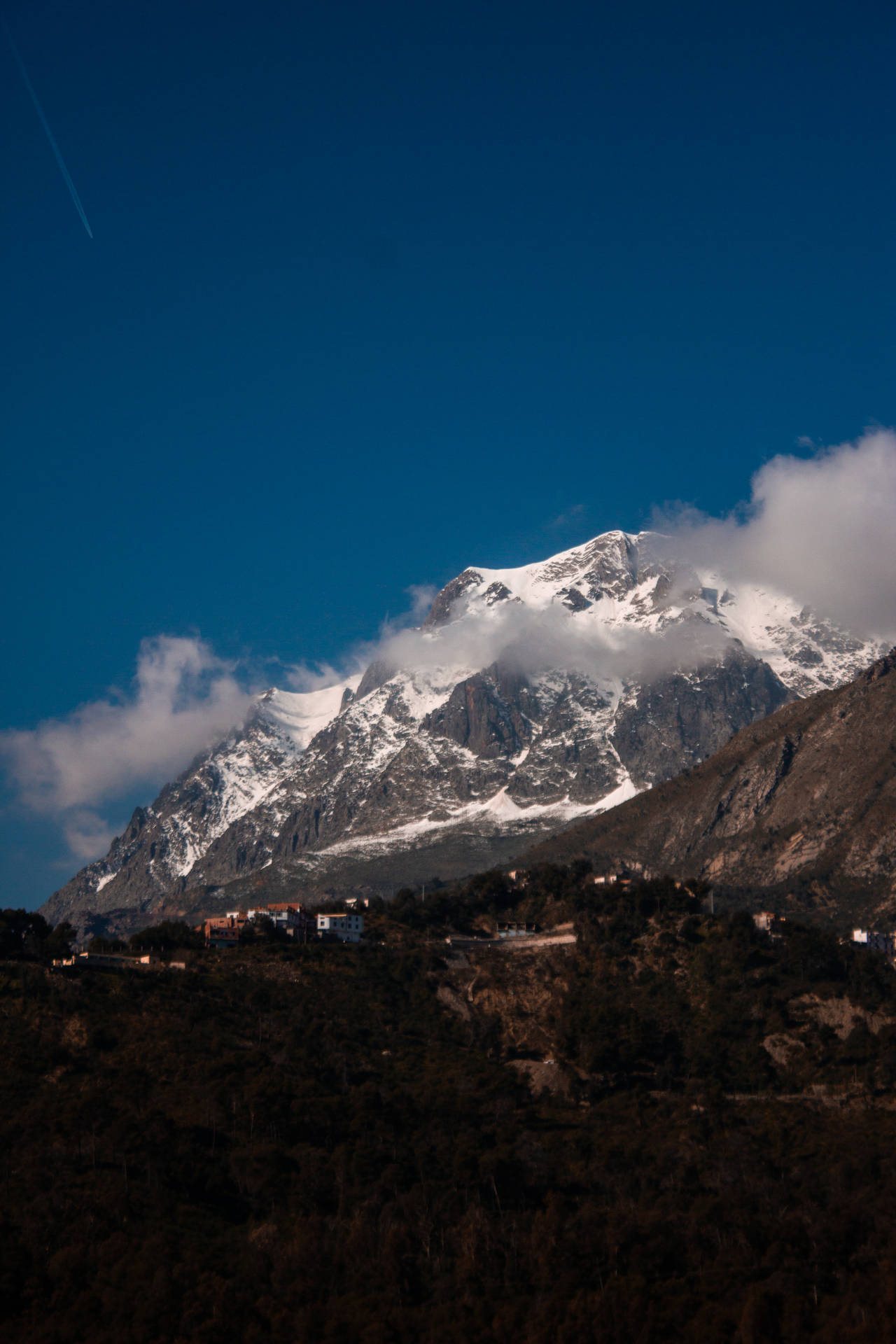 白雪皚皚的山峰在晴朗的藍天下聳立於雲層之上。