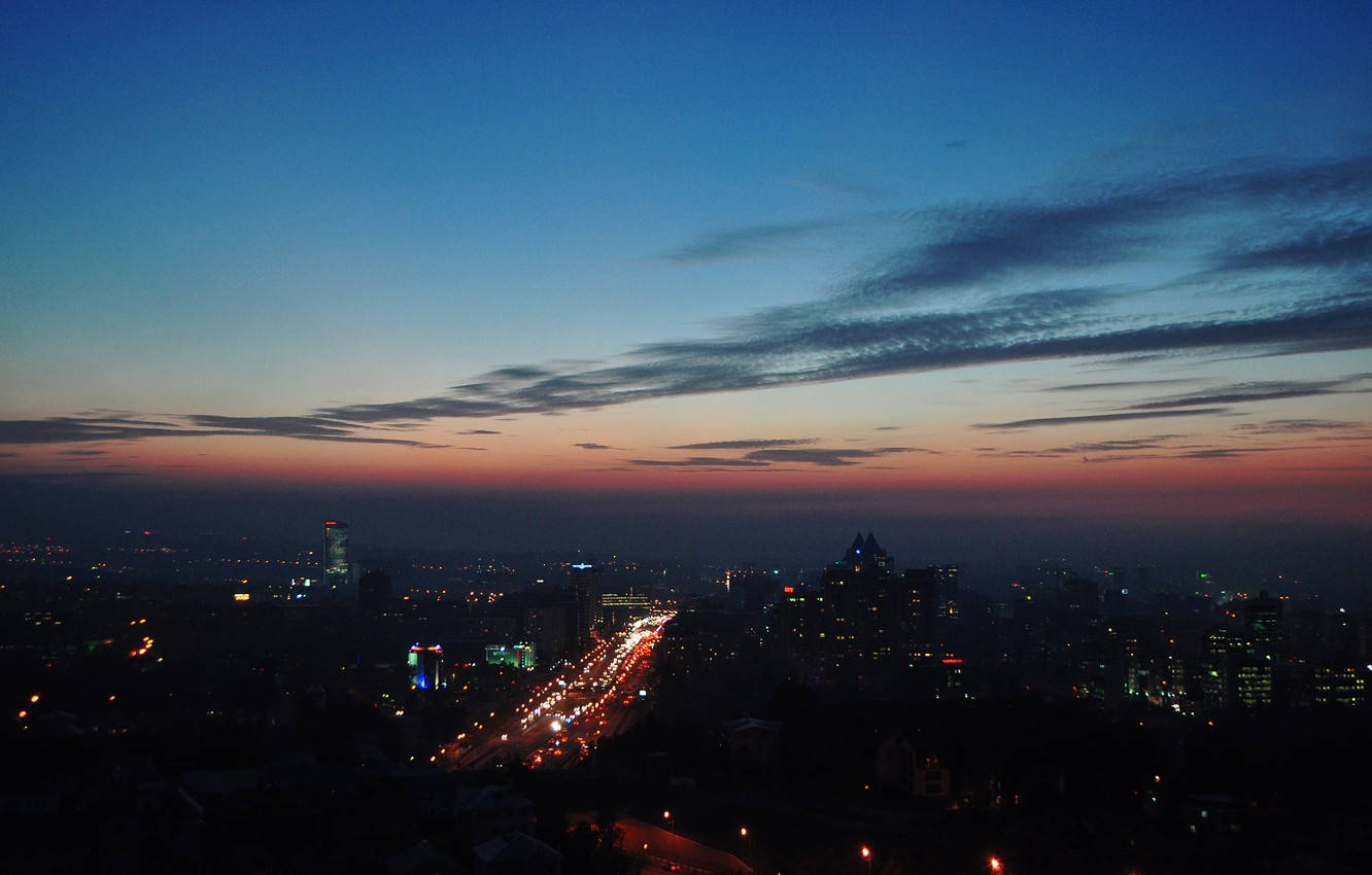 阿爾馬蒂夜景鳥瞰 壁紙 — 城市天際線在黃昏時分，車燈拉絲，天空從深藍漸變到柔和橙色。