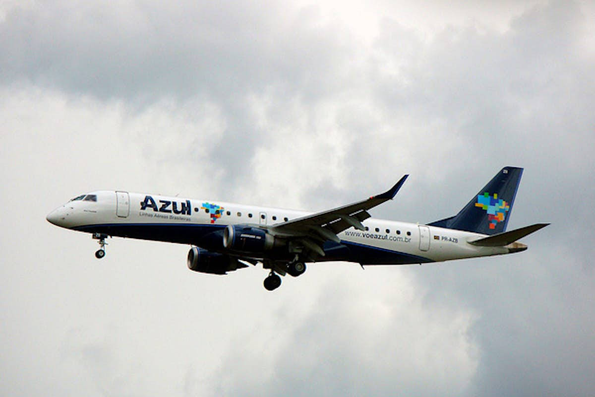 Azul Airlines飛機在雲層密佈的天空下放下起落架飛行。