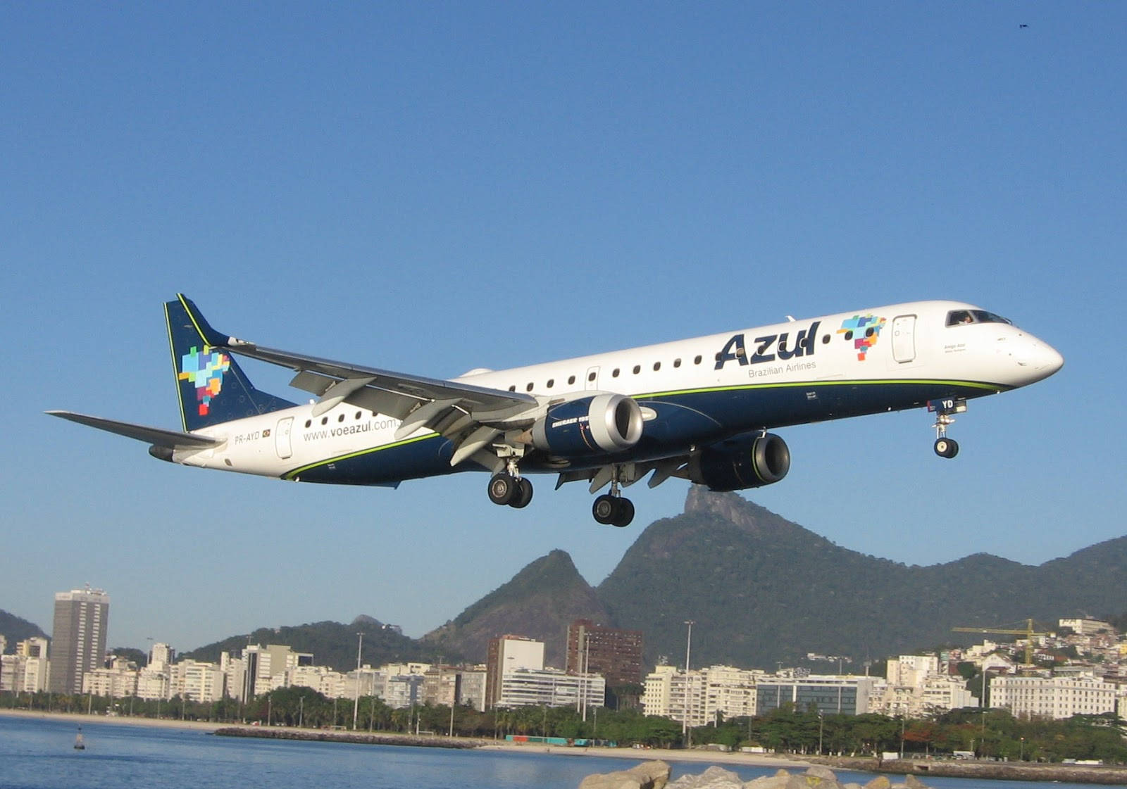 藍色巴西航空飛機在里約熱內盧上空降落，背景是山脈和城市。