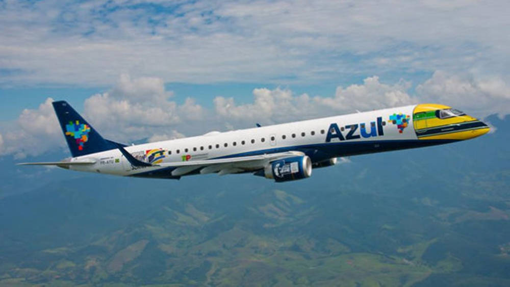 Azul Airlines飛機在部分多雲的天空下飛越山區地形。