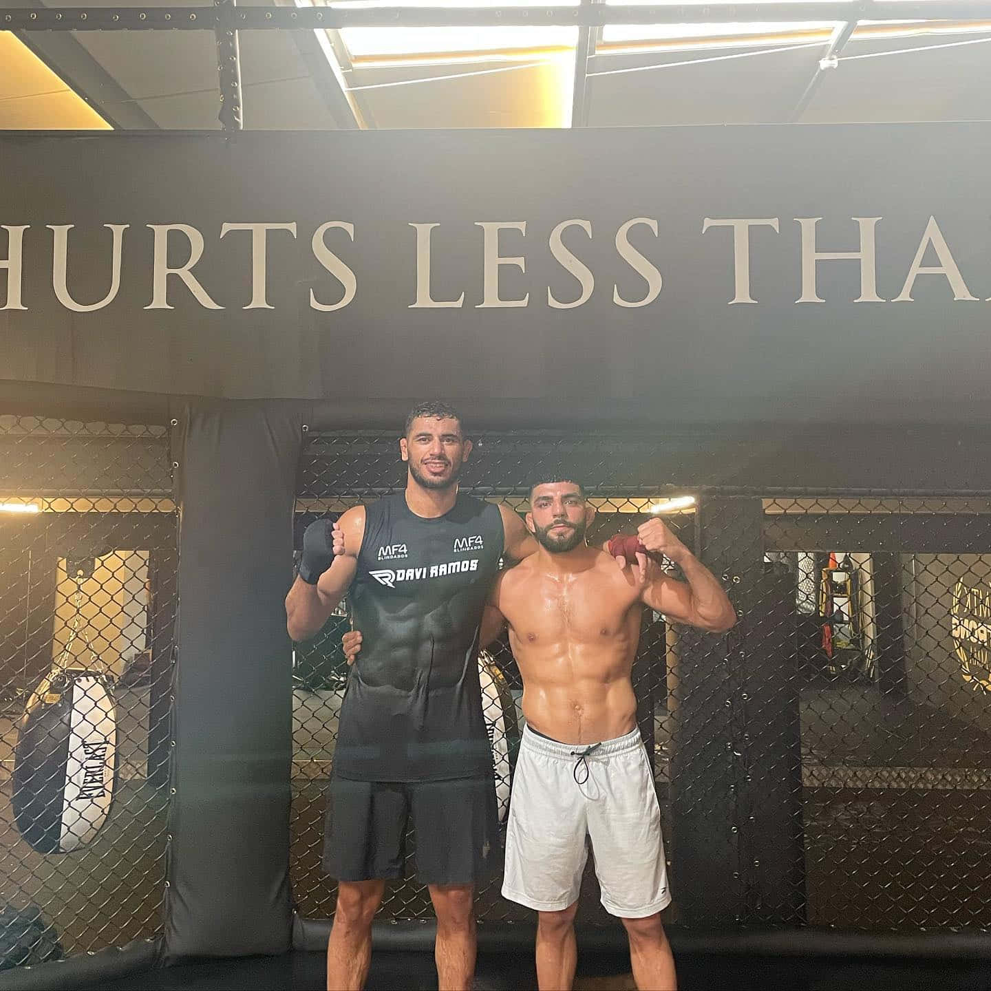 兩名赤膊和一名穿襯衫的肌肉男在MMA籠子內擺姿勢。