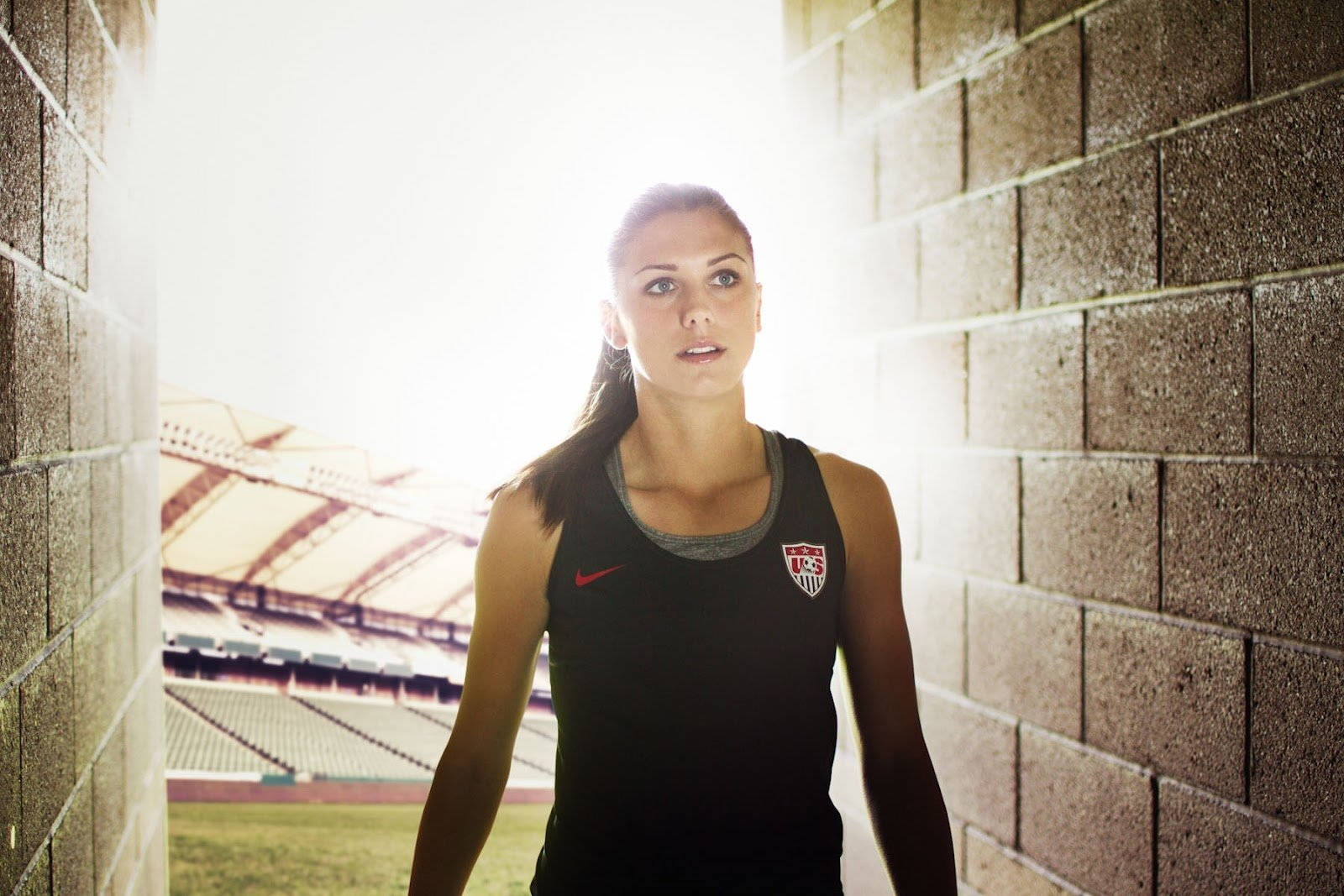 女足球員身穿黑色球衣，站在體育場隧道中，背後有明亮的光線。