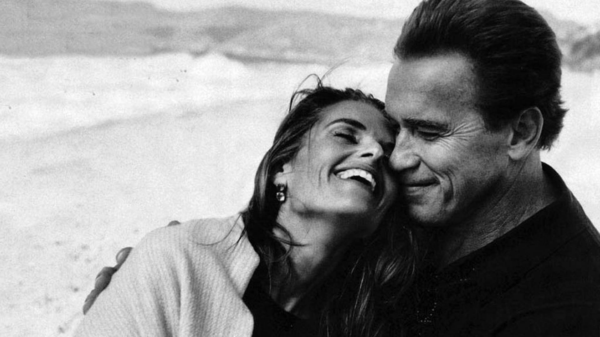 一對情侶在日落時分的海灘上笑著擁抱。