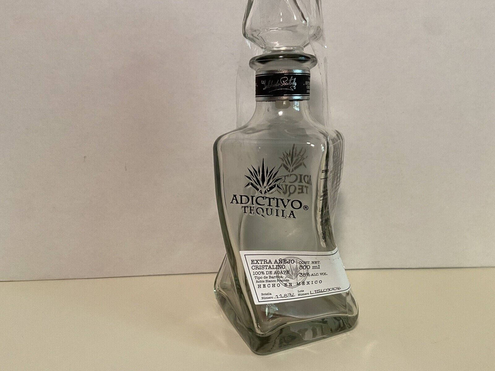 阿迪克蒂沃特級陳年水晶龍舌蘭 壁紙 — 一個透明玻璃瓶的Adictivo Tequila Extra Añejo直立於中性背景的平坦表面上。