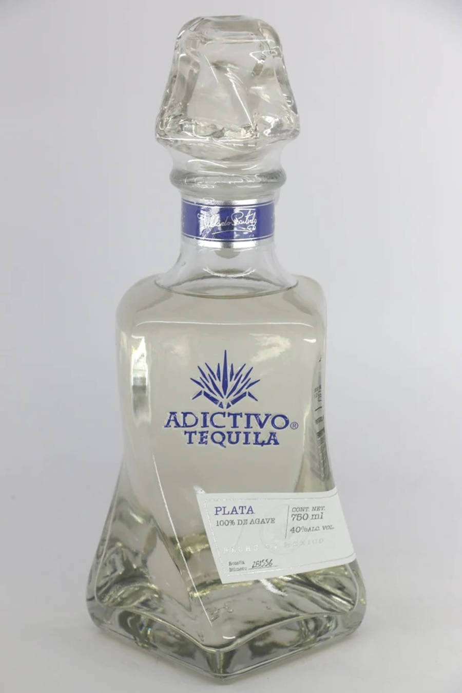 阿迪克蒂沃白龍舌蘭混合 壁紙 — 一個透明玻璃瓶的Adictivo Plata龍舌蘭酒，帶有刻面瓶塞和藍色標籤，立在純白色背景前。
