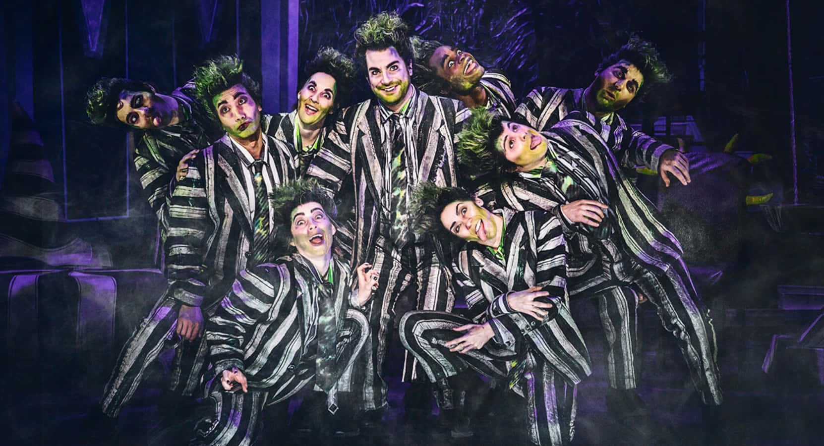 Beetlejuice 桌布 壁紙 — 阿達一族演員穿著黑白條紋西裝，在紫色舞台燈光和戲劇性煙霧下動態擺姿勢。
