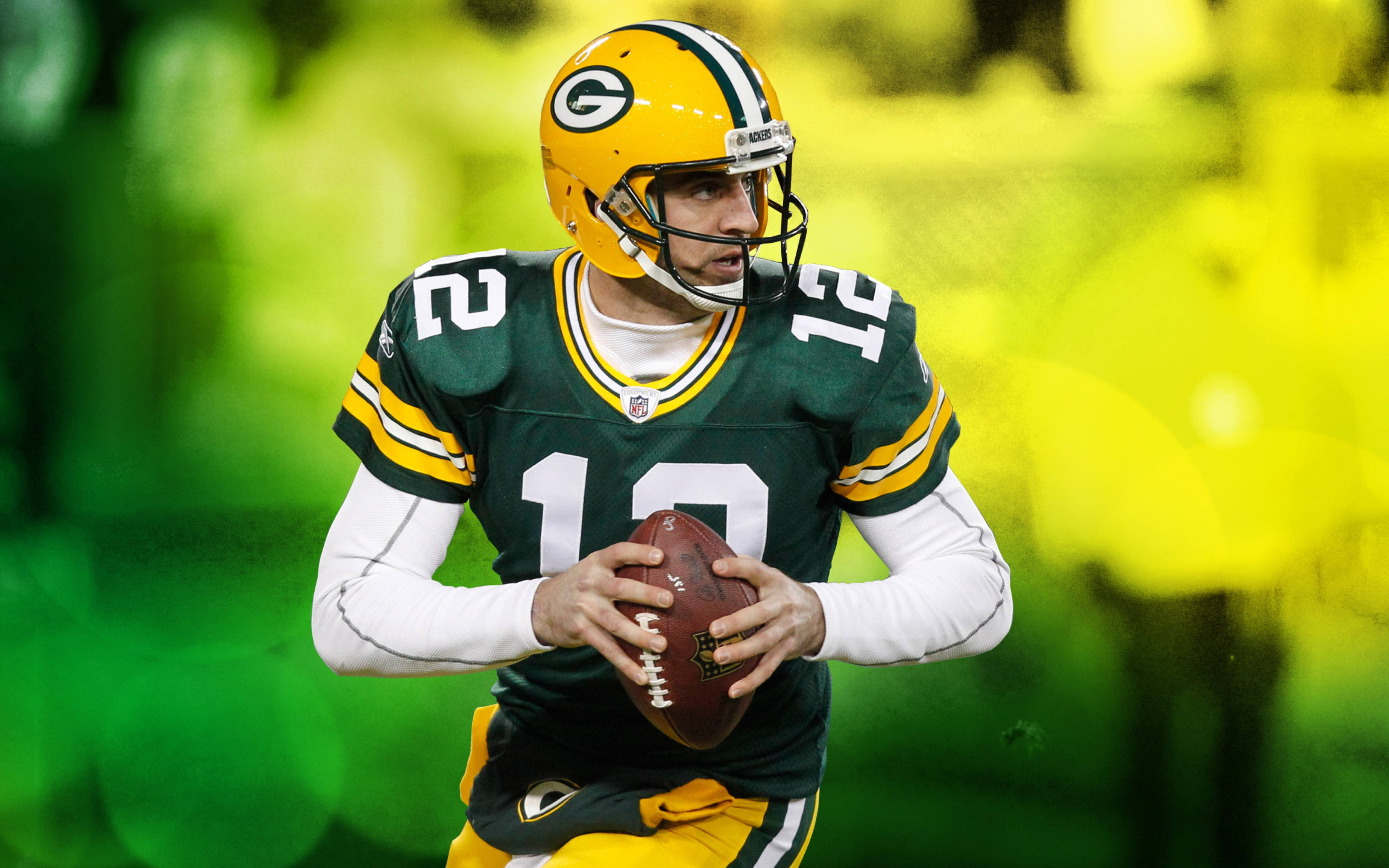 阿隆·羅傑斯 NFL 威斯康辛 壁紙 — 綠灣包裝工隊的四分衛穿著綠色和金色制服，手持橄欖球準備投擲，背景是模糊的體育場。