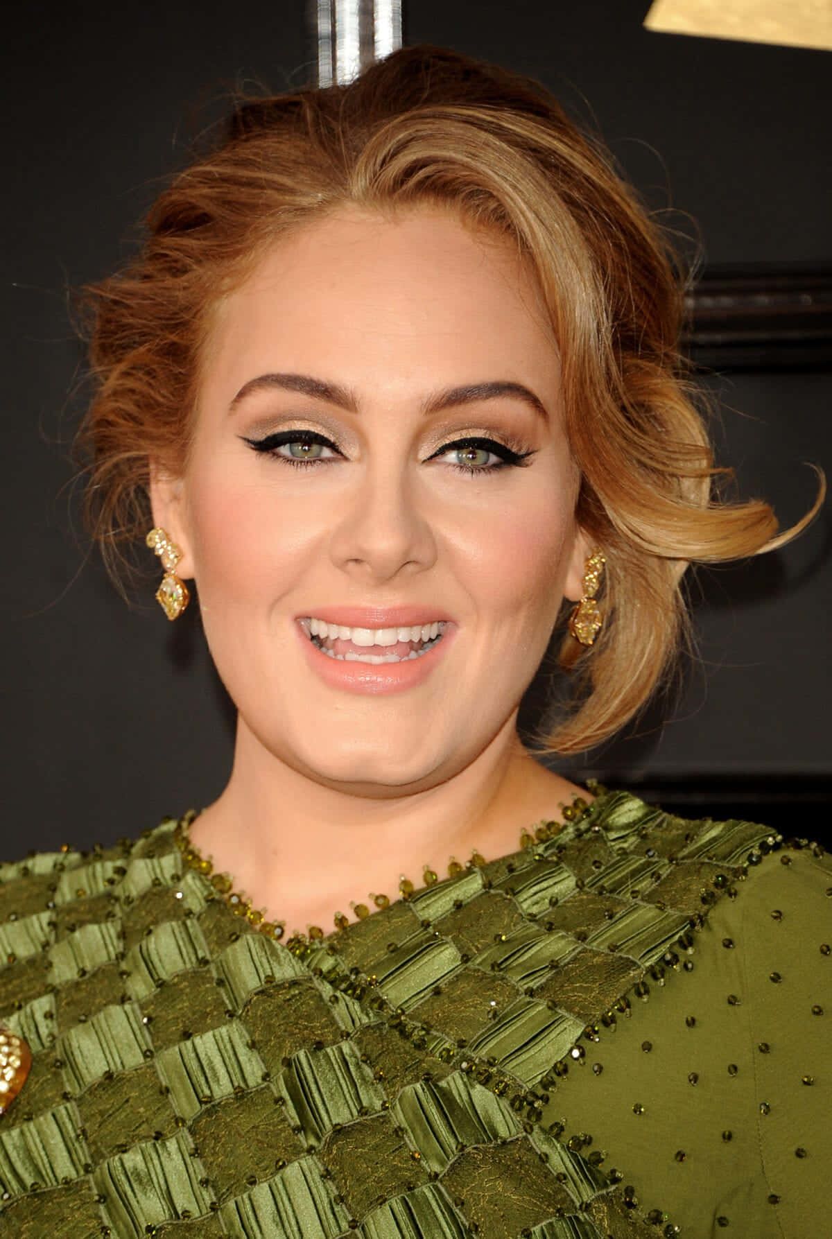Adele 在活動中穿著綠色珠飾連衣裙和金色耳環。
