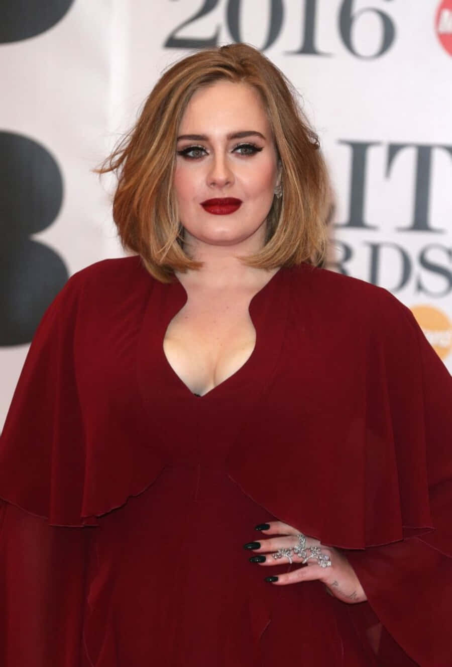 Adele 在2016年全英音樂獎上穿著紅色連衣裙，搭配大膽的紅唇和黑色指甲。