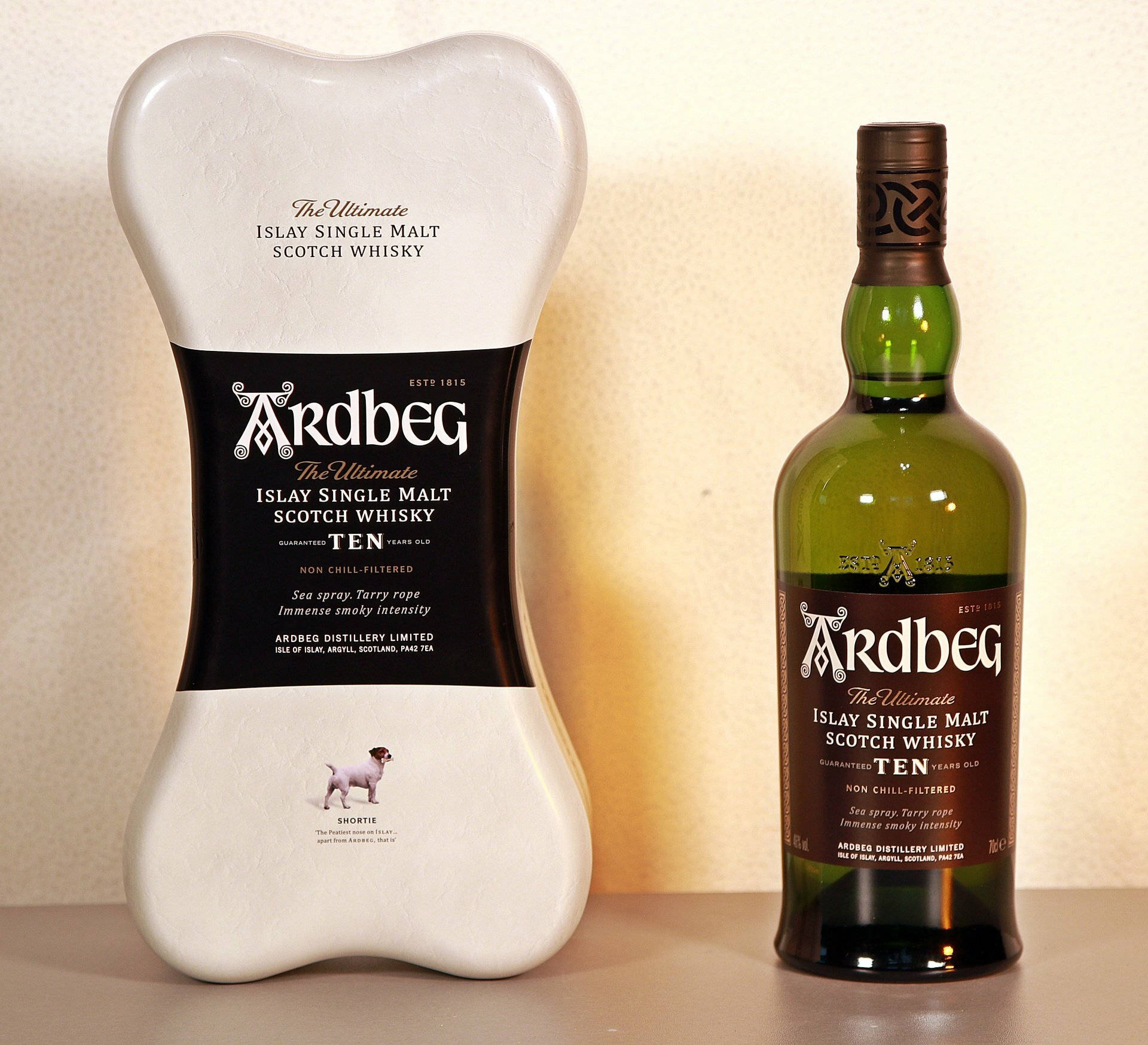 Ardbeg Ten Year Old威士忌的骨頭形狀罐頭和綠色酒瓶，附有小狗插圖。