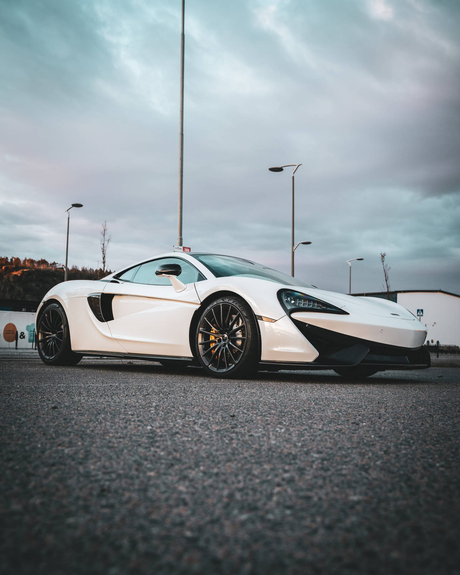 白色McLaren跑車停泊在瀝青路上，背景陰天。