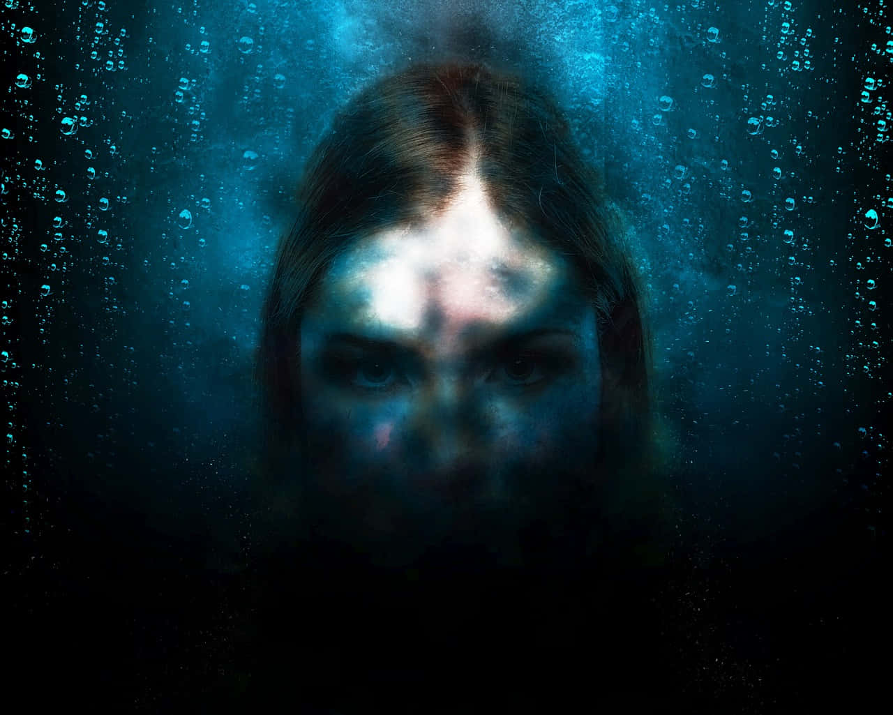 陰暗孤寂的水下視角 壁紙 — 一幅令人難忘的水下肖像，描繪一位女性的臉龐被一道光束照亮，周圍環繞著氣泡和深藍色的海水。